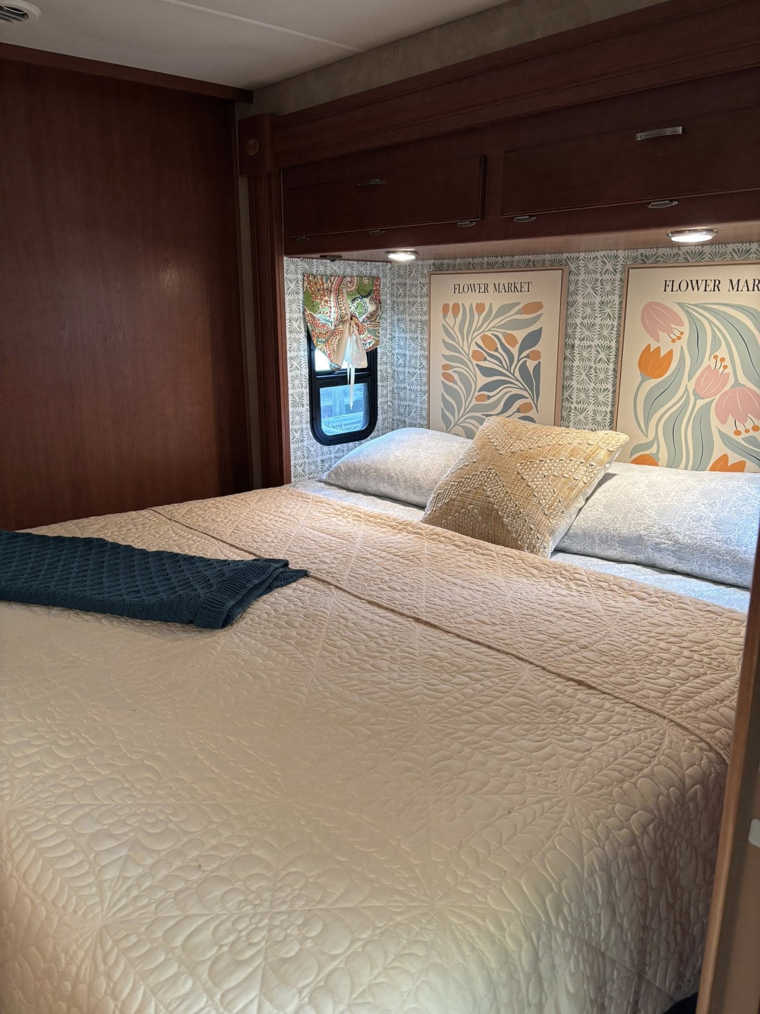 An RV rental bedroom with a cream quilted bed, teal throw, and floral art against patterned walls.. Georgetown Georgetown Motorhome 2011