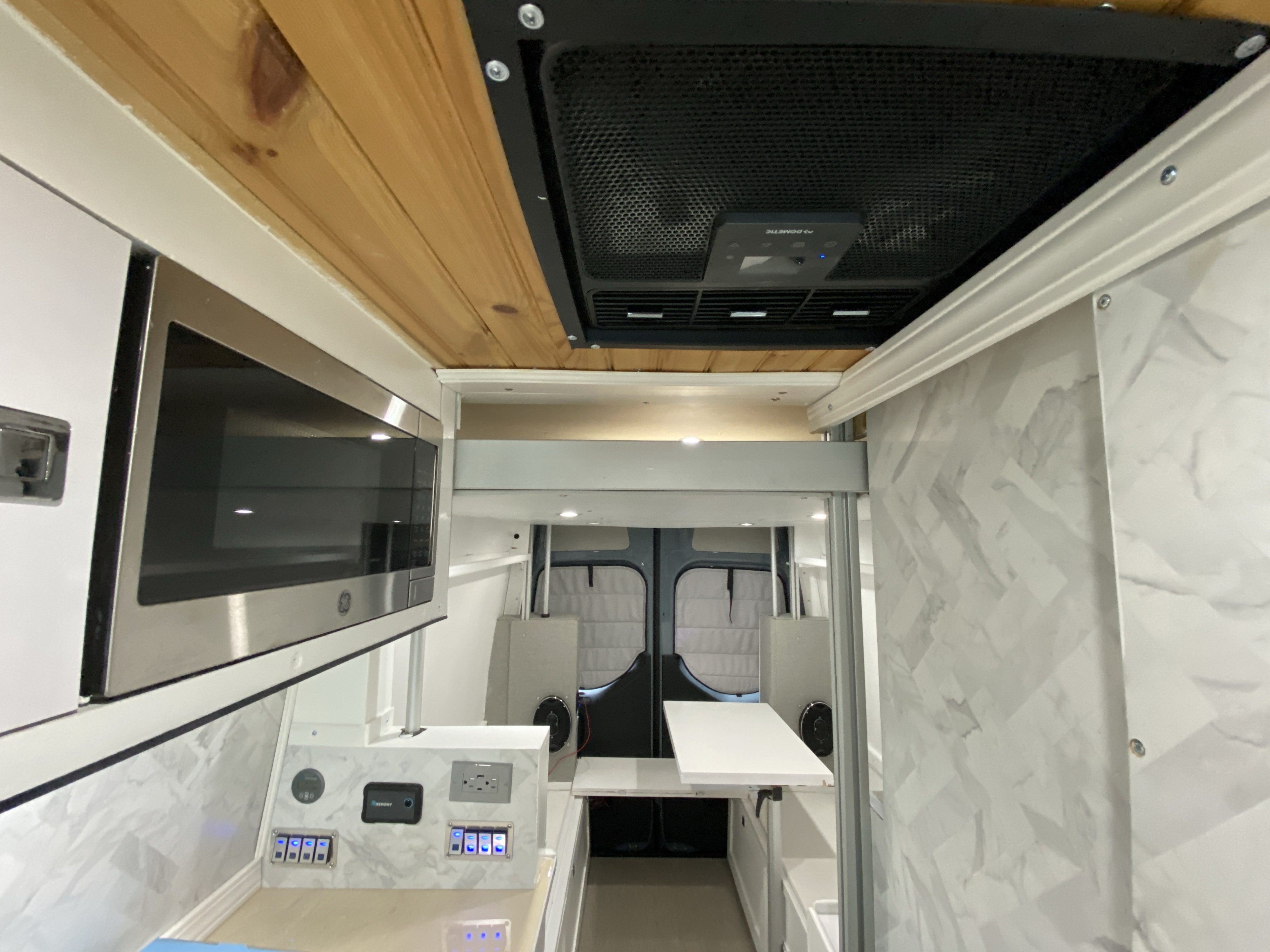 Luxurious RV rental interior featuring a GE microwave, Dometic AC, and sleek white & wood design.. Mercedes-Benz Sprinter 2500 4x4 2021