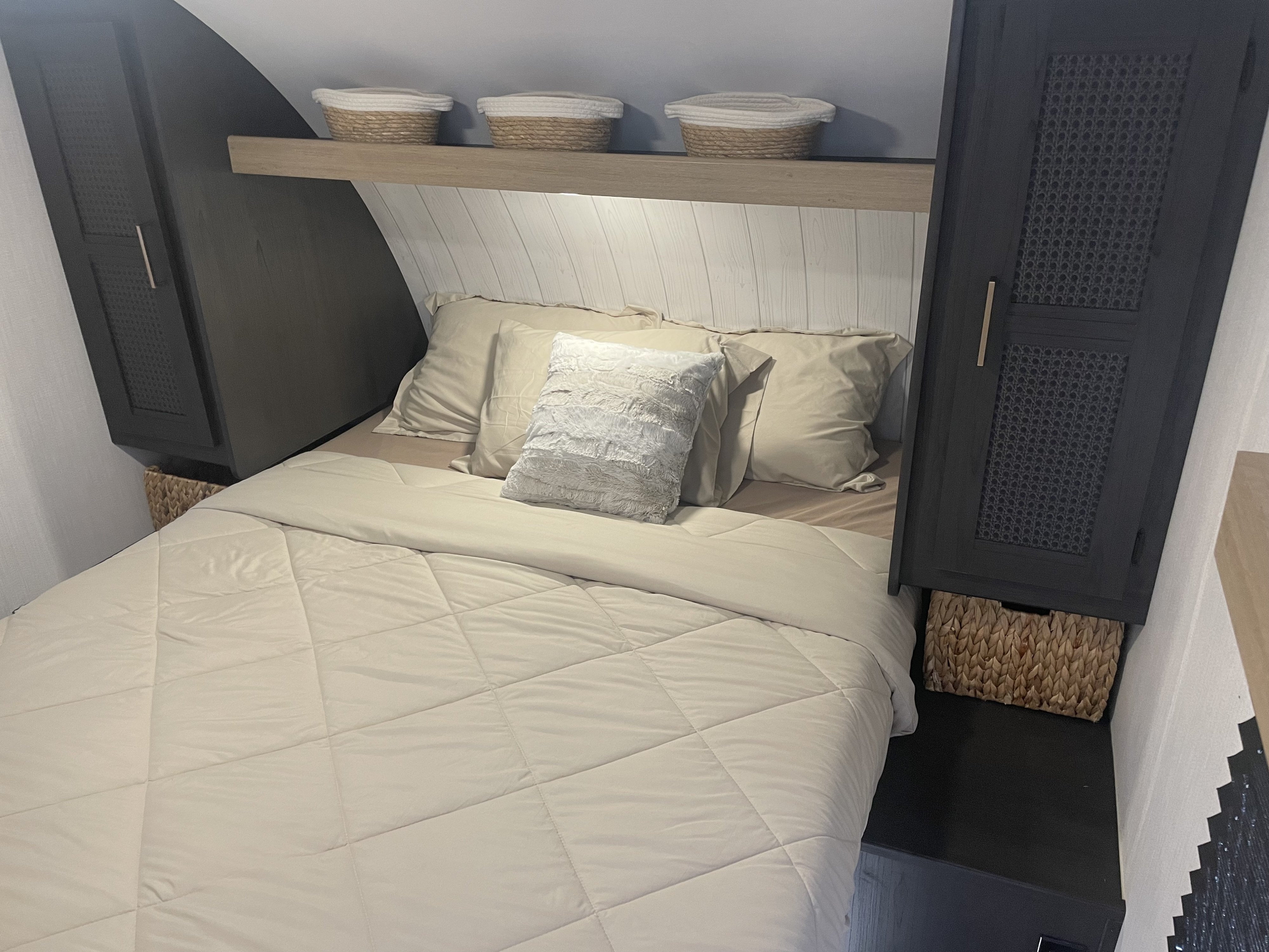 Cozy RV rental bedroom featuring a queen bed with light bedding, overhead storage, and accent baskets.. Heartland RVs Pioneer Trail Blazer 2024