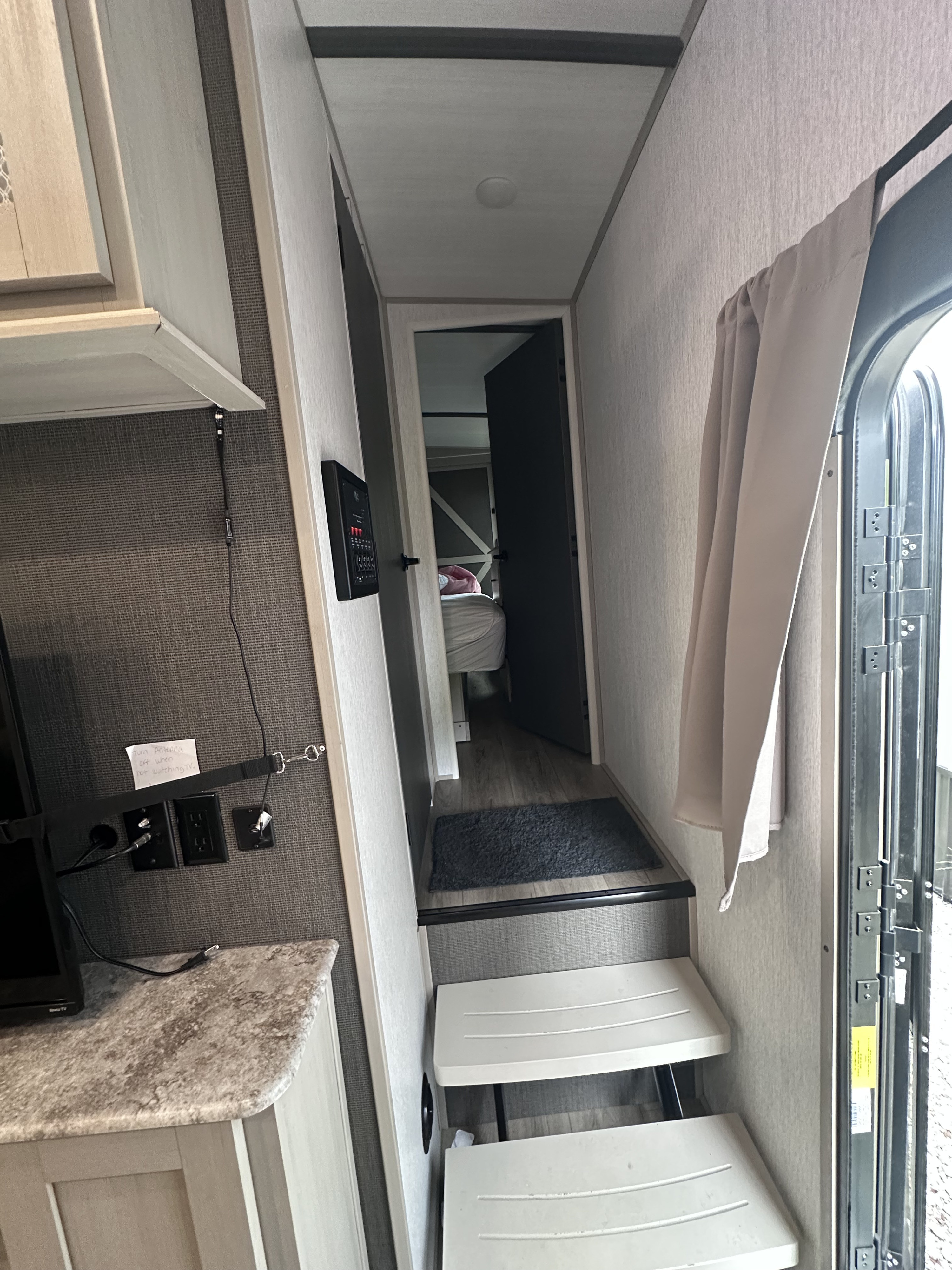 RV rental interior: Steps lead to a hallway with a bedroom view, control panel, and an open entrance door with a curtain.. Forest River Salem Hemisphere 2022