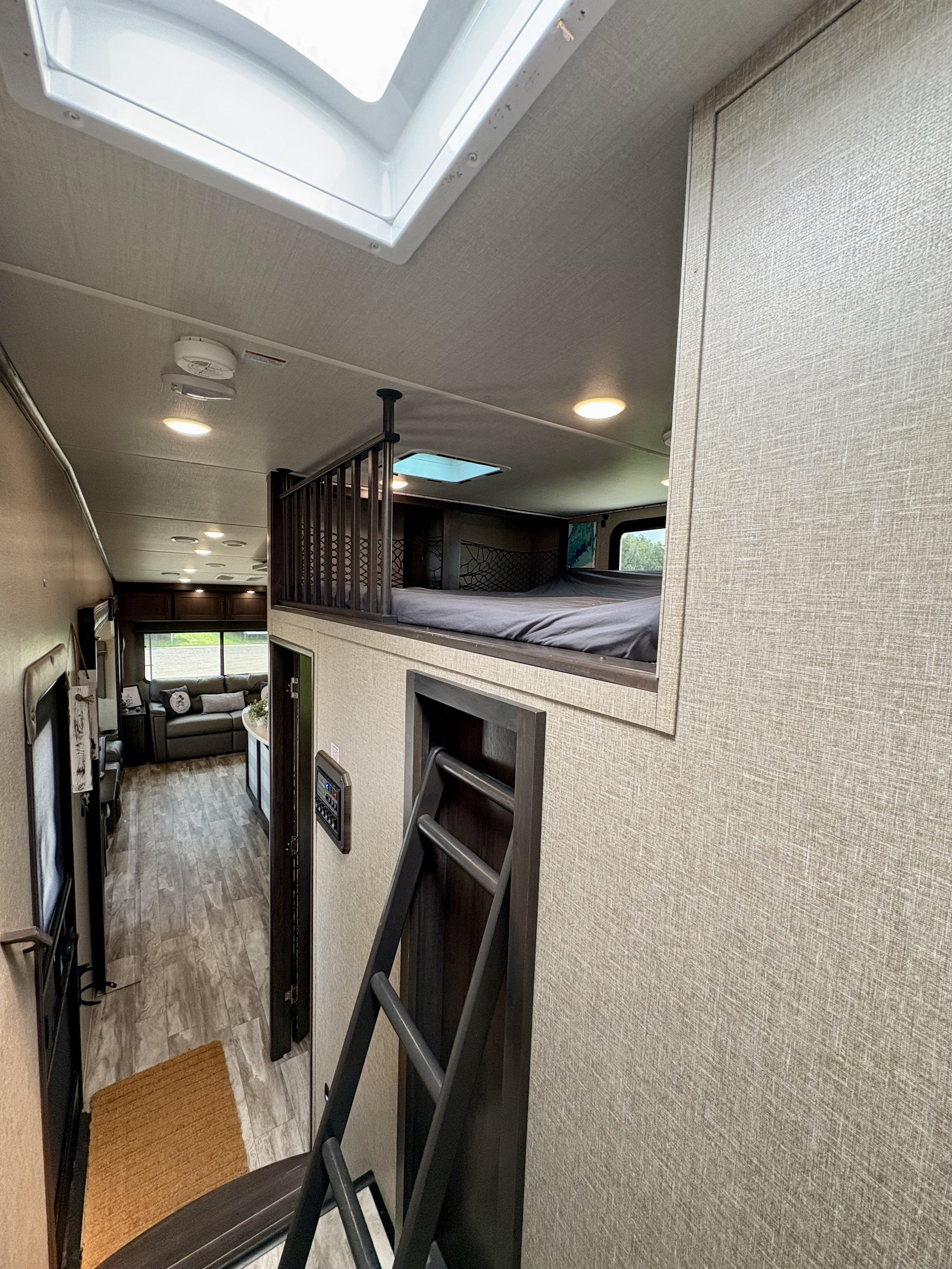 Spacious RV rental interior featuring a cozy loft bed, living area, and modern design. Perfect for travel!. Grand Design Reflection 2022
