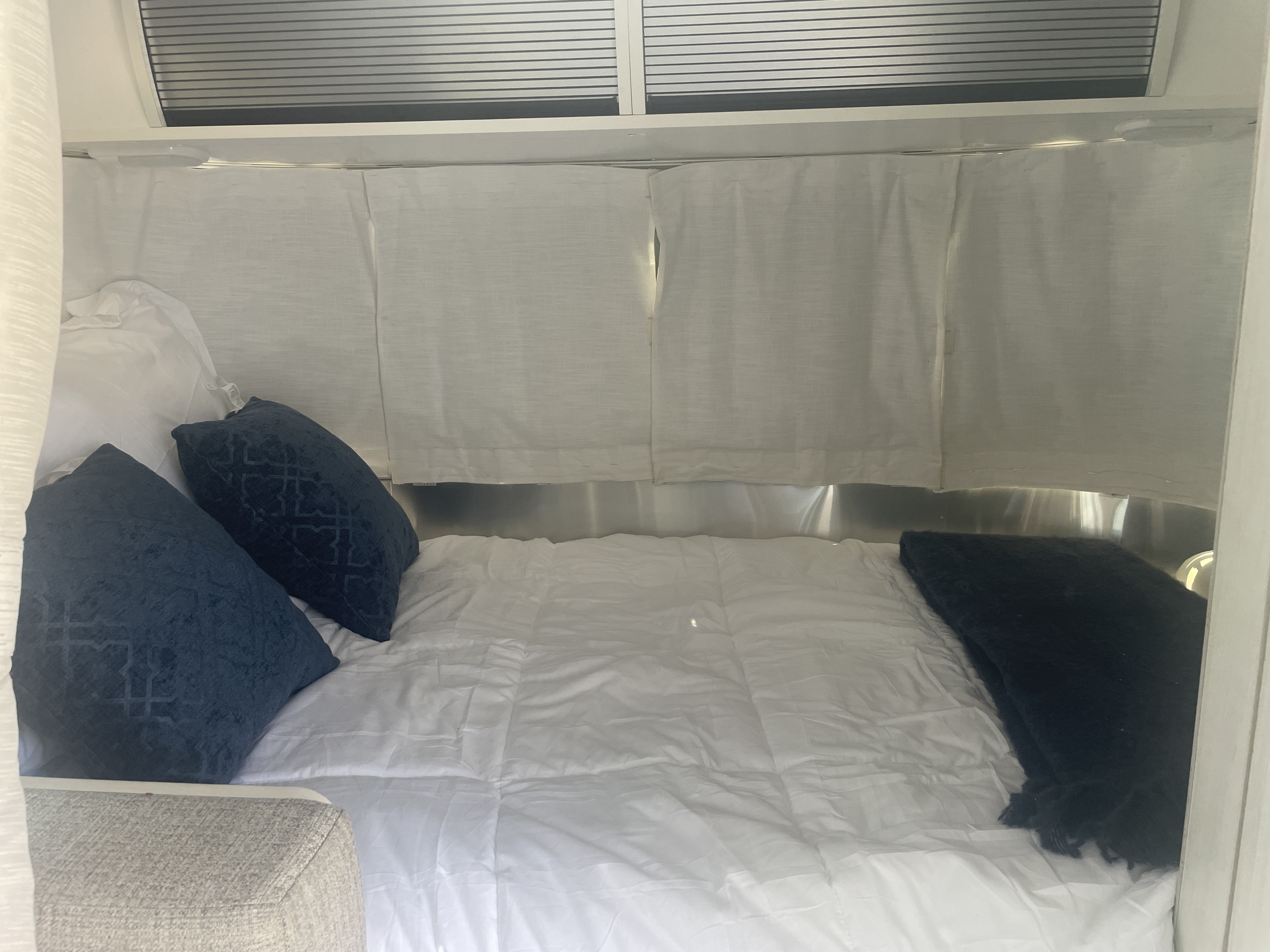 Airstream RV rental bedroom with crisp white bed, blue pillows, and a clean, bright interior.. Airstream Bambi 2020
