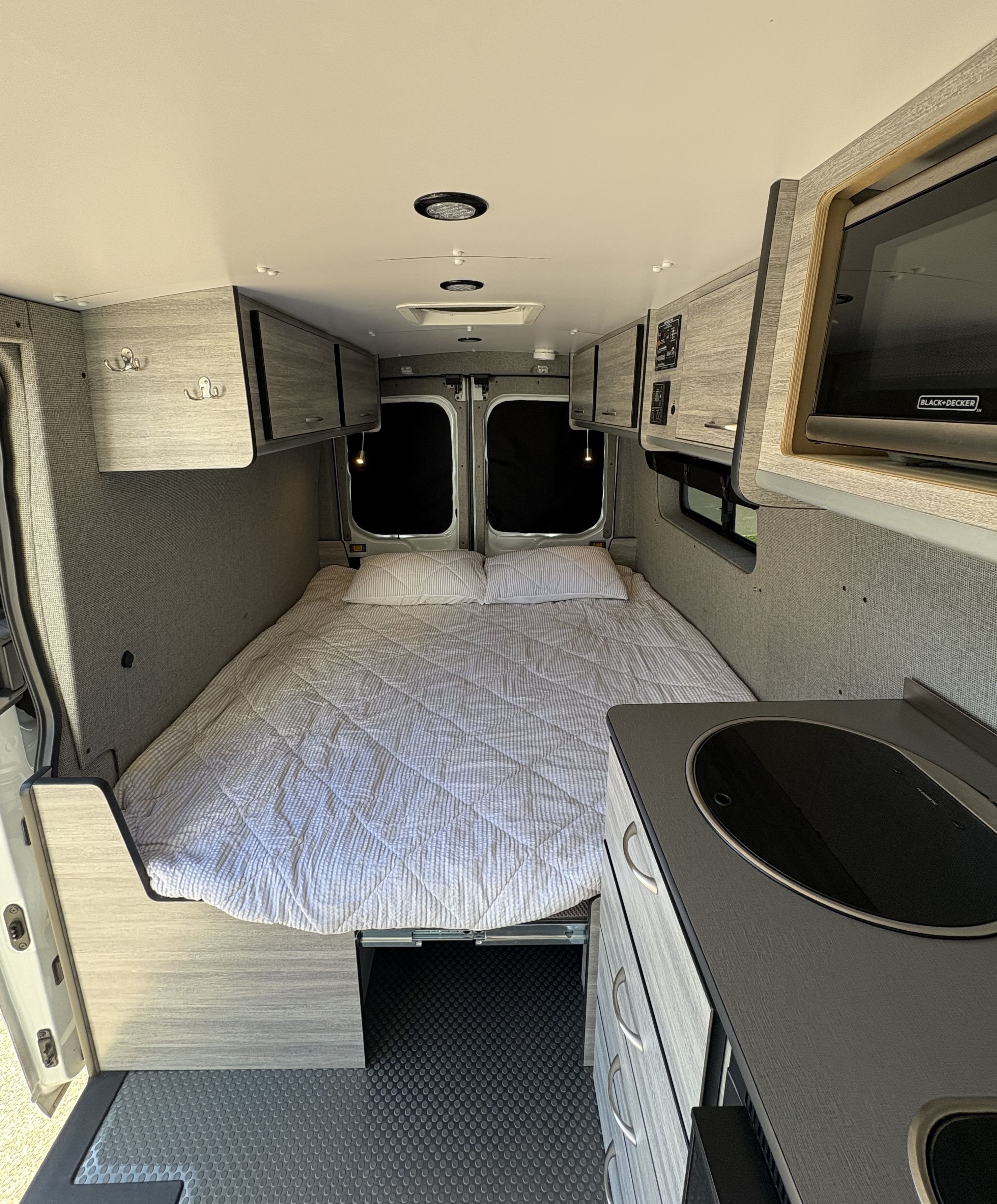 Spacious camper van interior, perfect for an RV rental adventure. Features a comfortable bed, kitchenette, and ample storage.. Ford Transit 2017