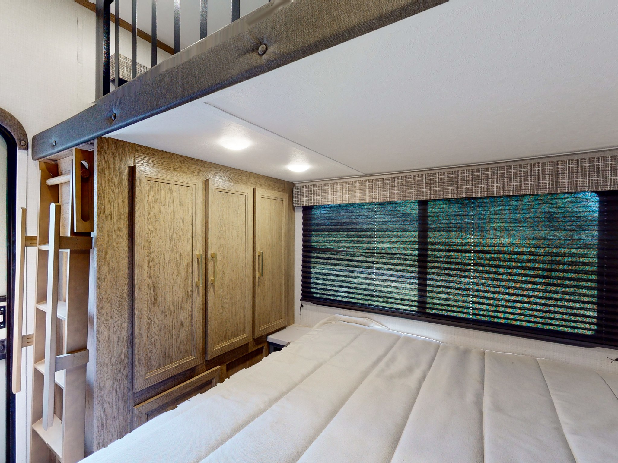 Explore this cozy RV rental bedroom interior with ample wood cabinets, a large window, and a ladder leading to a loft bunk.. Keystone RV Eddie Bauer Signature 360LF 2024