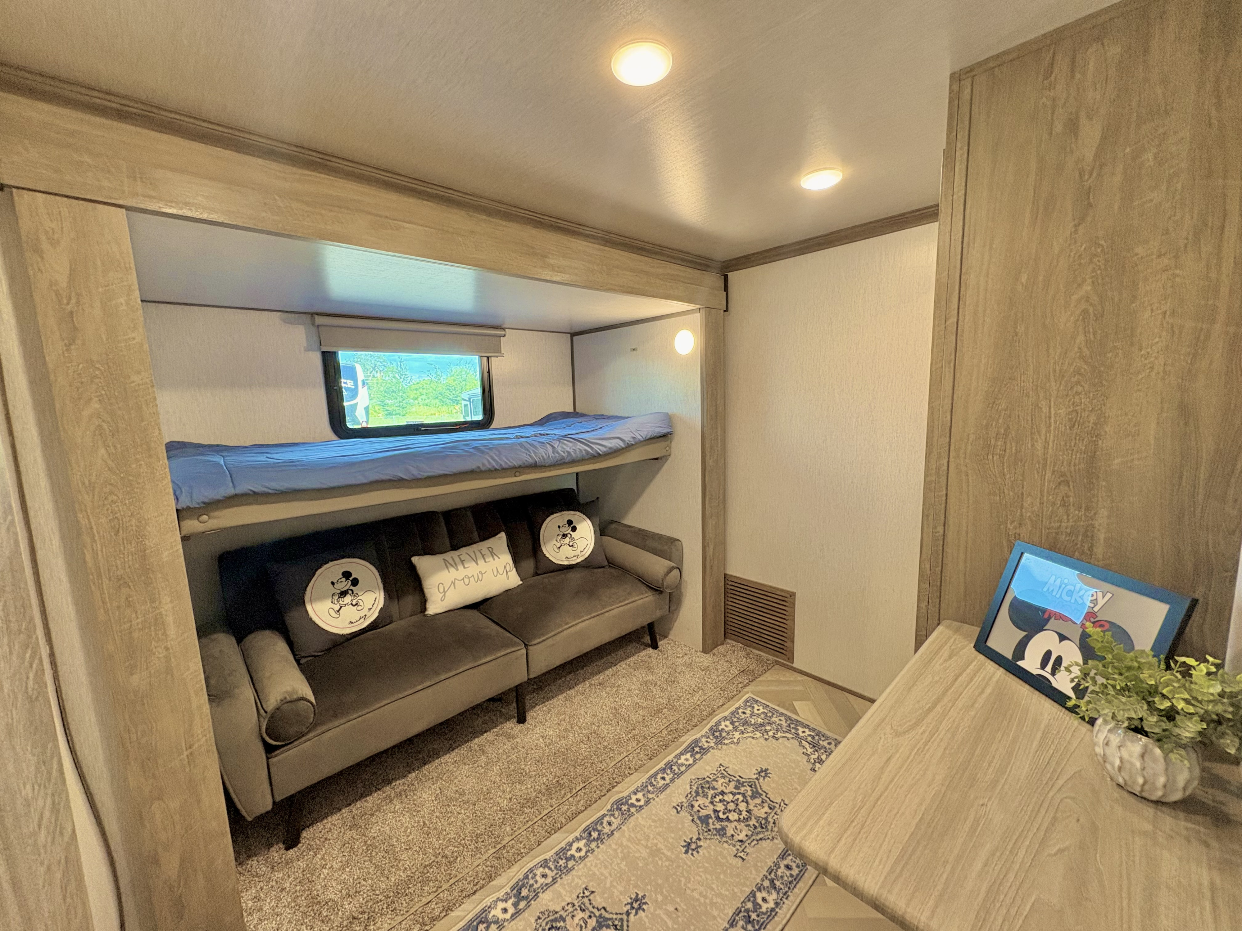 Cozy RV rental interior featuring bunk beds, a sofa with Mickey Mouse decor, and a dining table.. Forest River Salem Hemisphere 2022