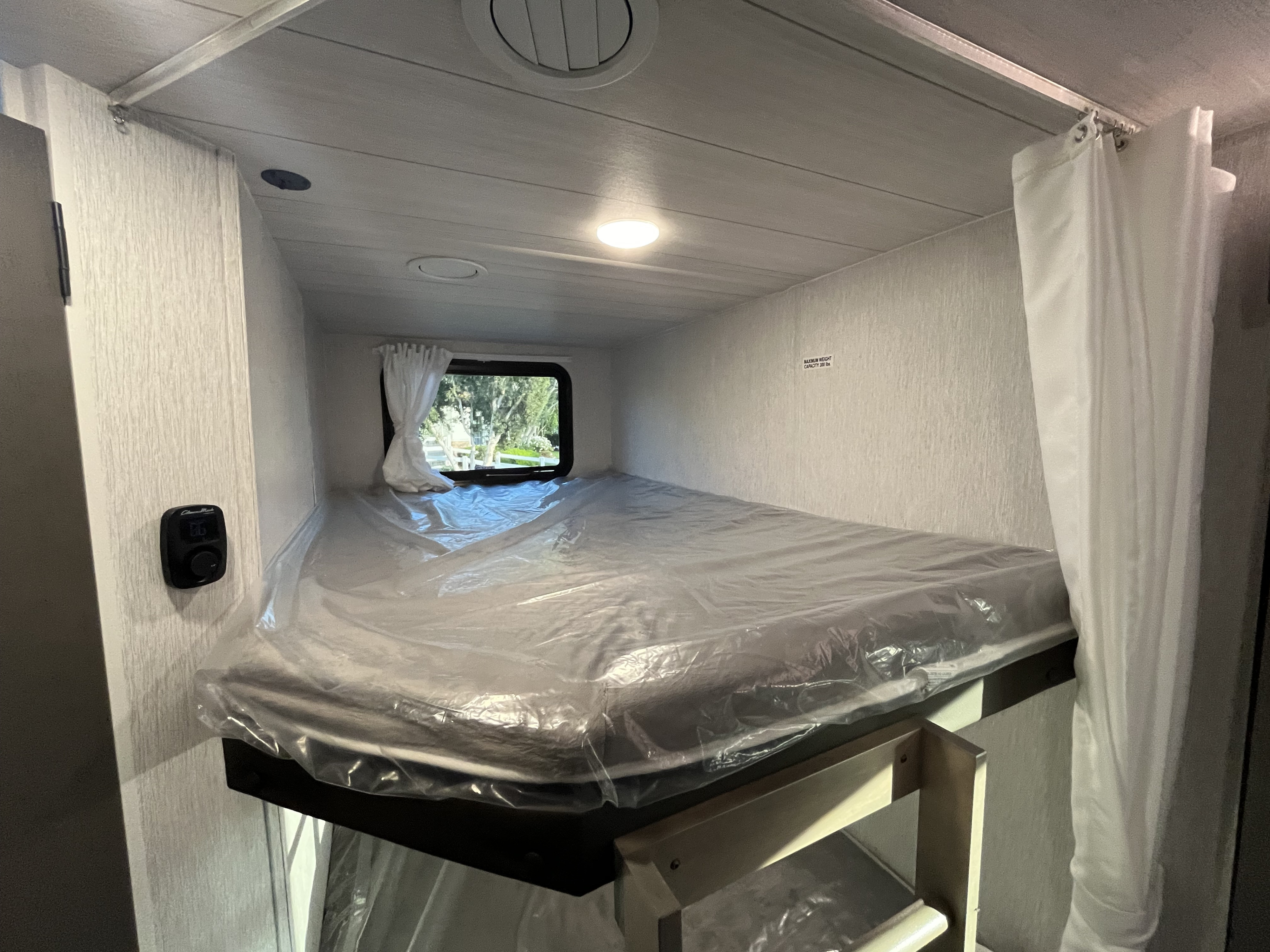 This RV rental features a cozy bunk bed with a new mattress, perfect for compact sleeping in a travel trailer.. Forest River Evo 2490 2023