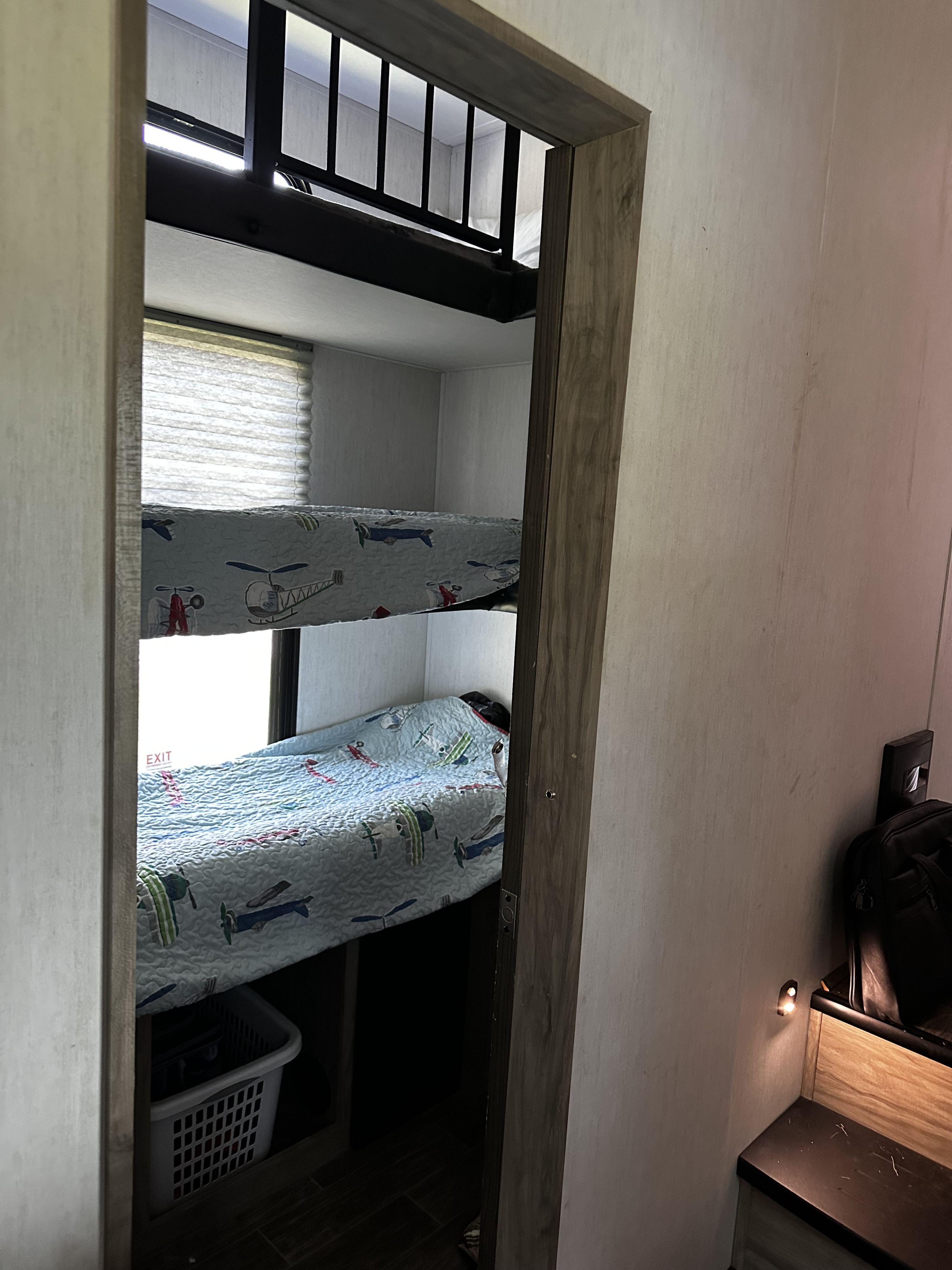 RV rental interior featuring cozy bunk beds with airplane quilts and an emergency exit window.. Forest River Cherokee Arctic Wolf 2023
