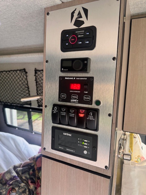 Inside an **RV rental**: a control panel with Kenwood stereo, tank monitor, lighting, and power controls for comfortable travel.. Antero Adventure Motors Antero Adventure Motors Class B 2022