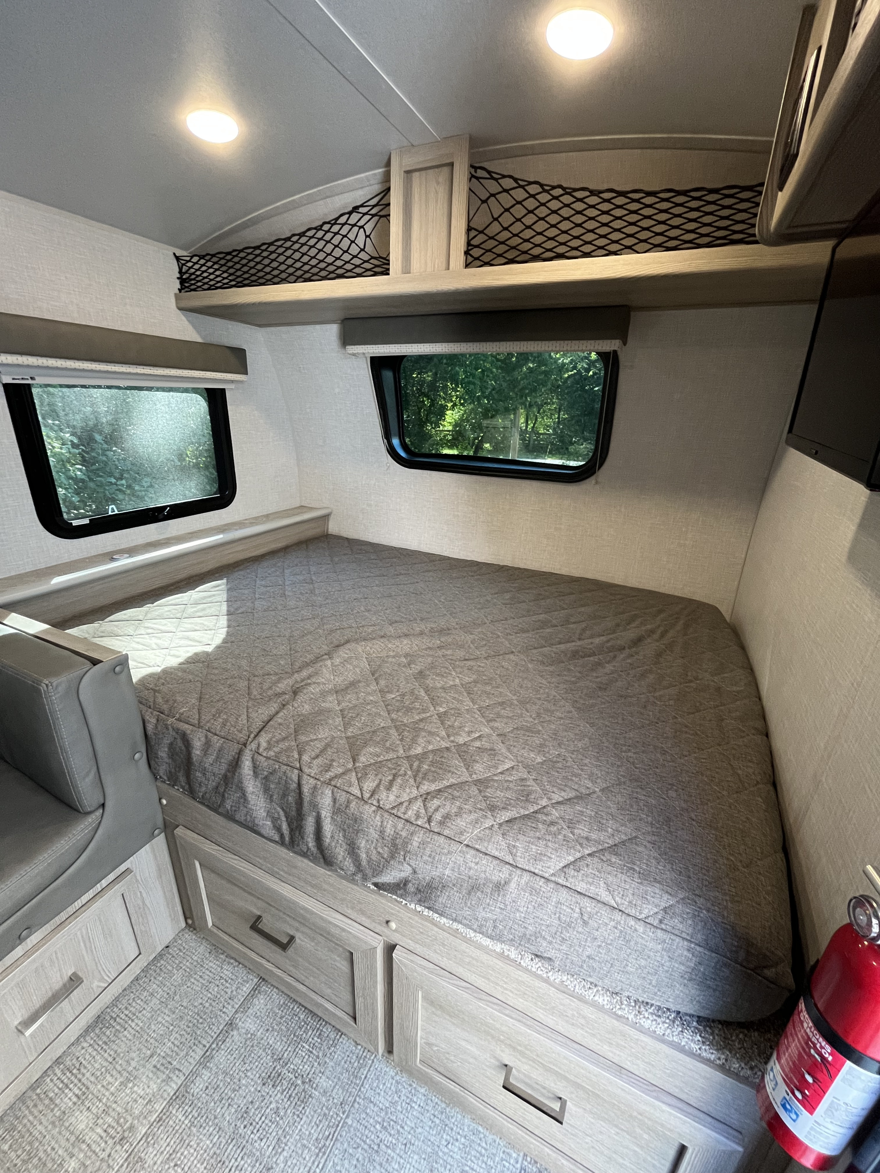 Comfortable sleeping area in this RV rental, featuring a quilted bed, under-bed storage drawers, and large windows for scenic views.. Forest River GeoPro 19BH 2021