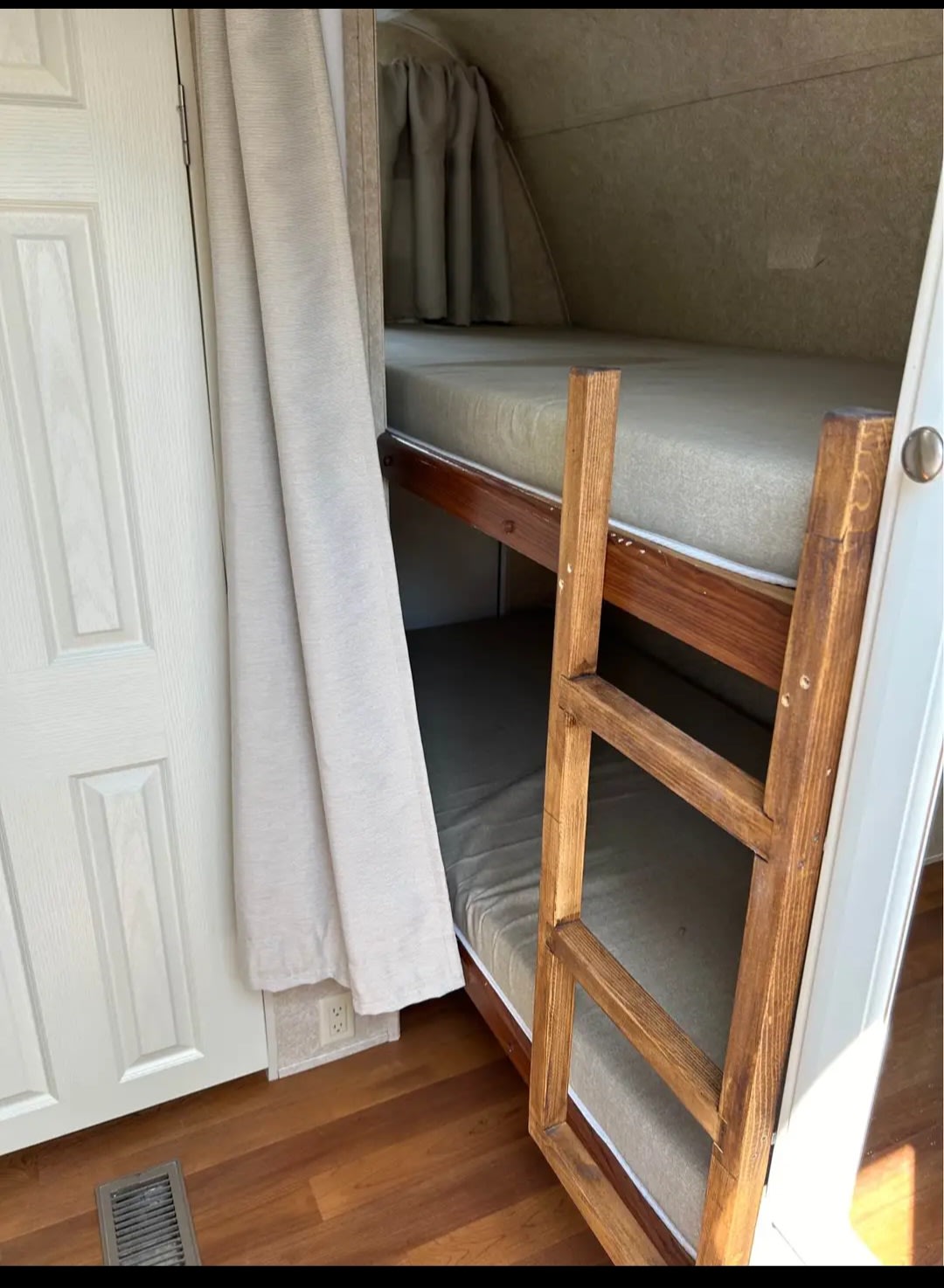 This RV rental offers a compact sleeping area with two bunk beds, a wooden ladder, and a privacy curtain.. Keystone RV Outback 2008