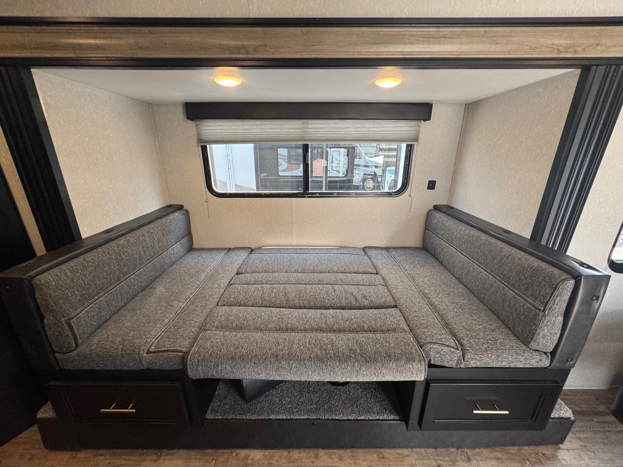 RV rental interior shows a gray dinette area that converts to a bed, with a window and overhead lights.. Forest River Cherokee Wolf Pup 2021