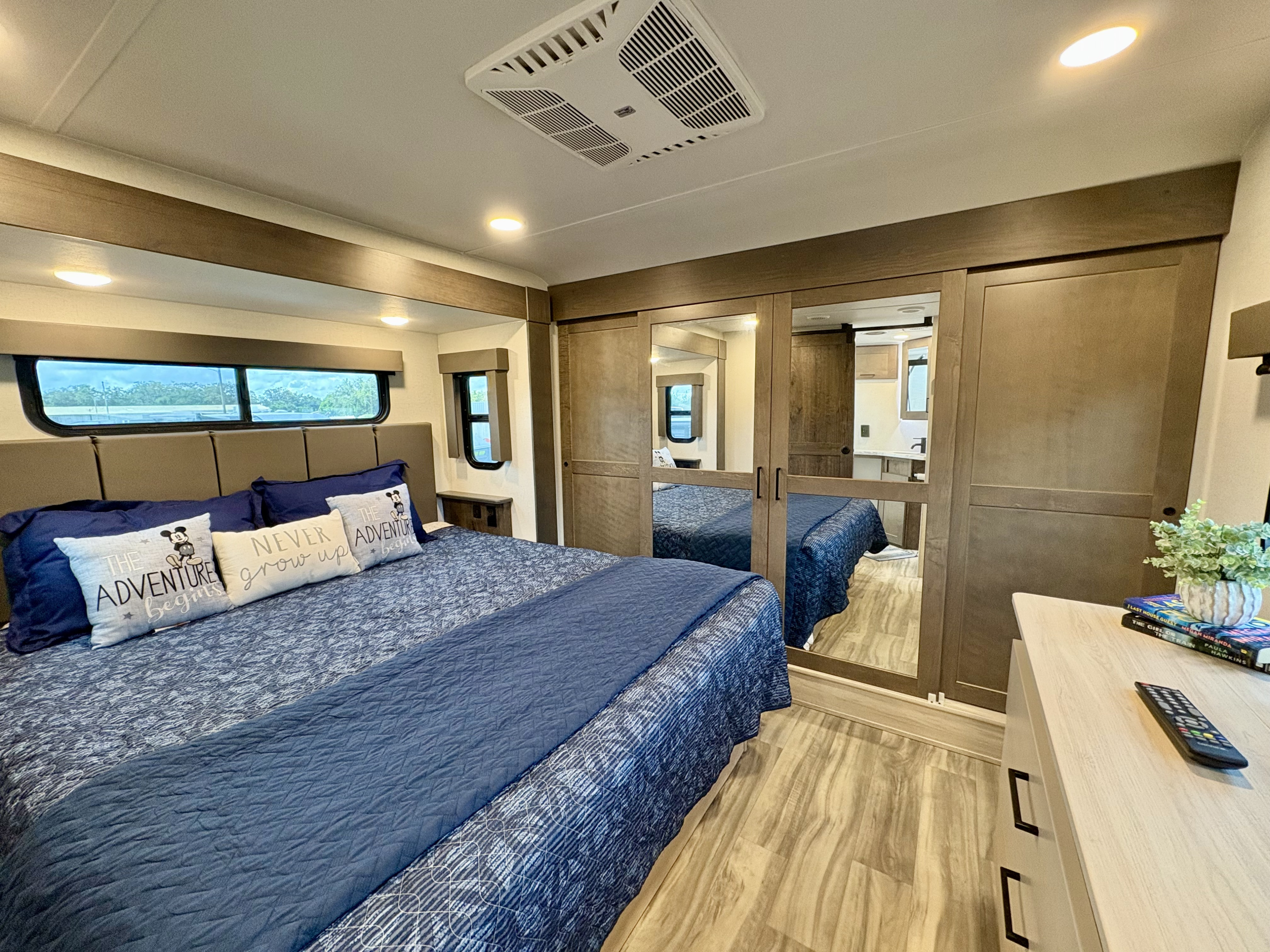 Spacious RV rental bedroom with comfy bed, AC, mirrored storage, and modern decor for your next adventure.. Alliance RV Valor 2023
