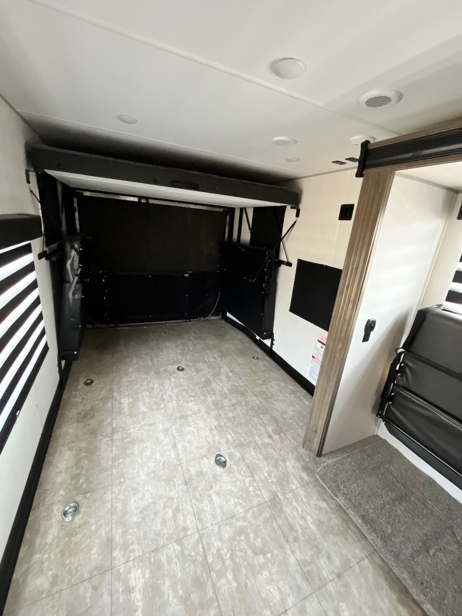 Spacious RV rental interior featuring a raised lift bed and floor tie-downs, perfect for a versatile 'garage' or living area.. Forest River Vengeance 2022