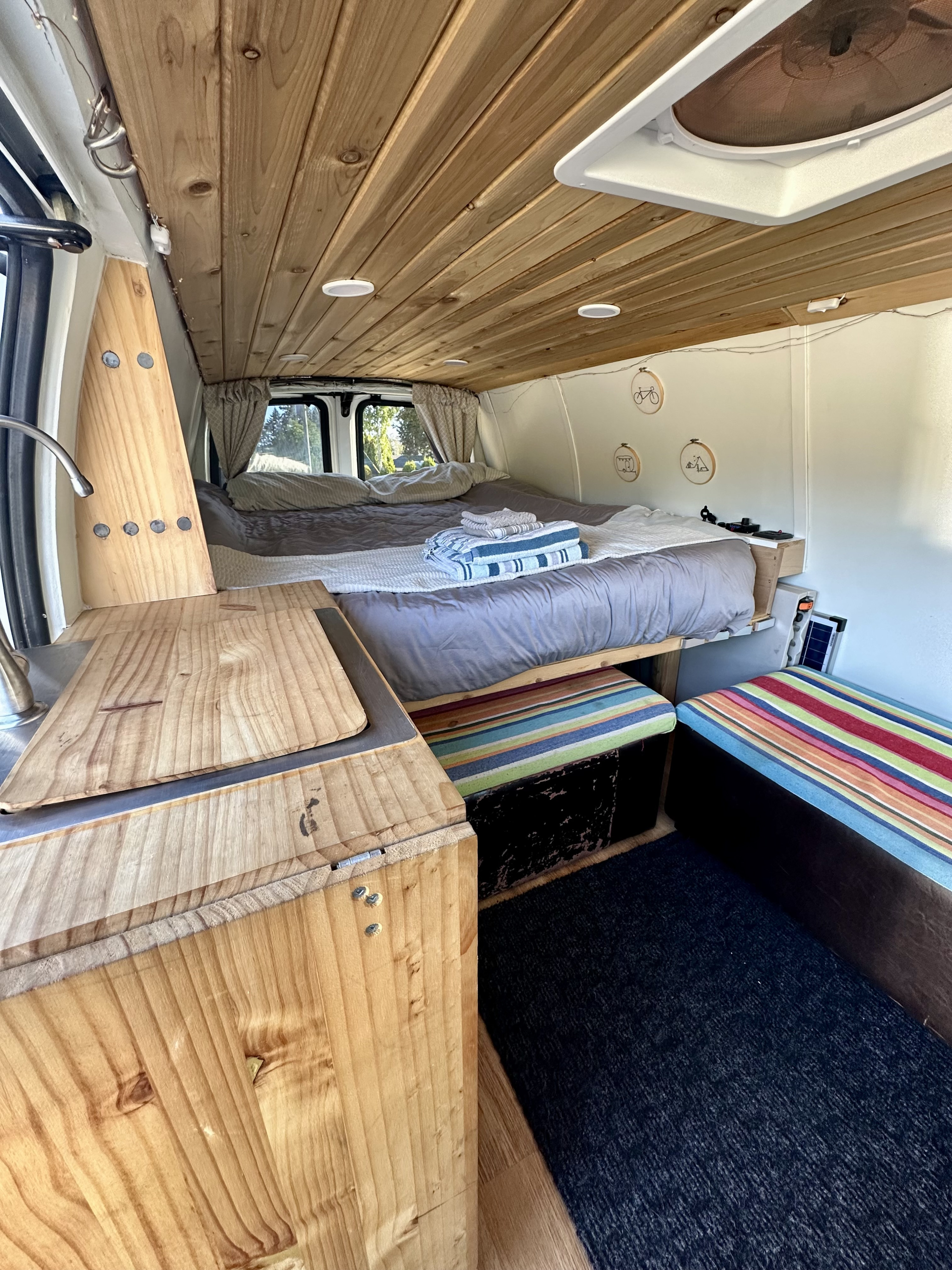 Inviting RV rental interior: wood-paneled ceiling, comfortable bed, functional kitchen, and seating.. Chevrolet Express 3500 2006