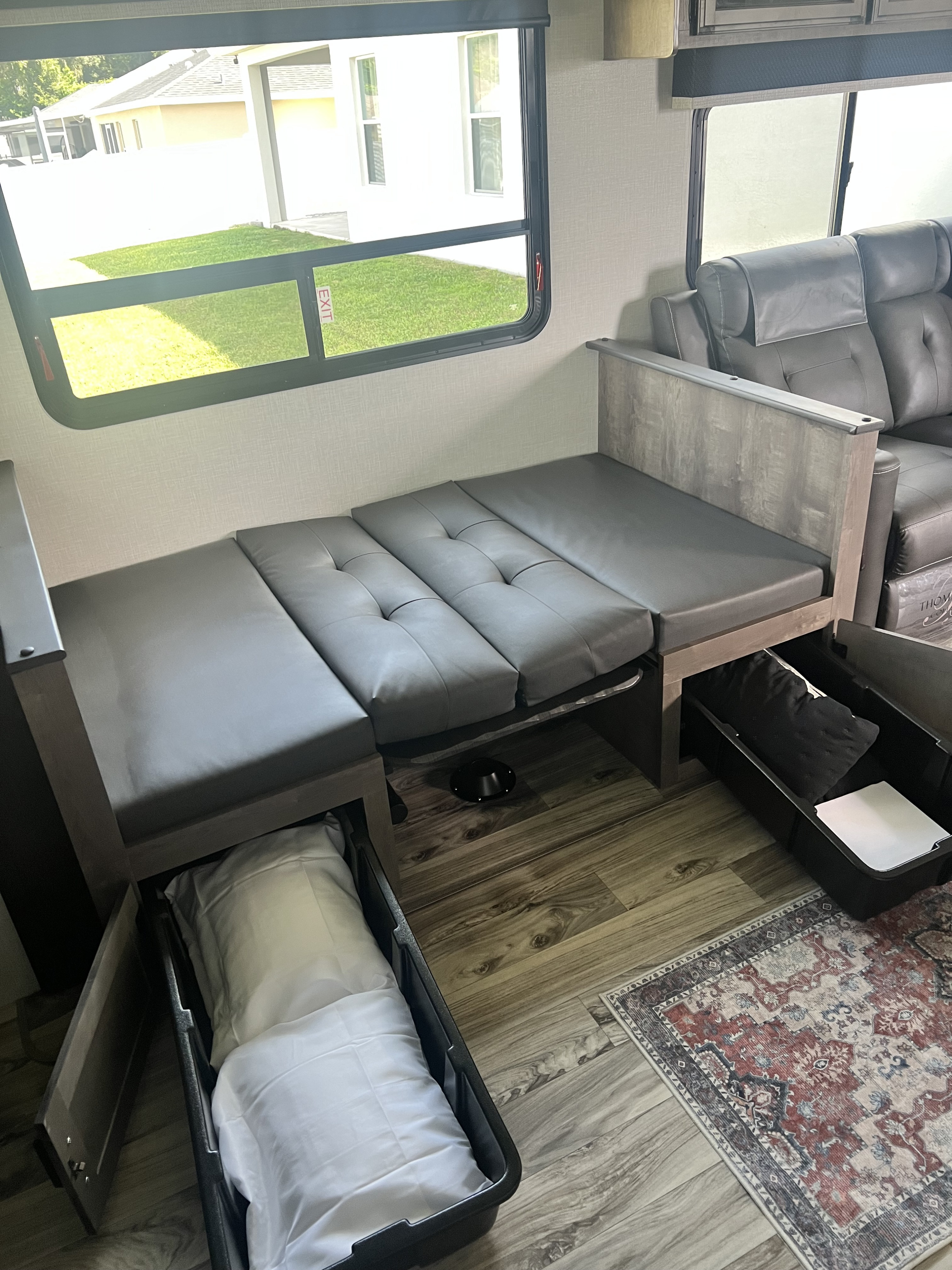 RV rental interior: convertible dinette seating, under-seat storage for bedding, and wood-look flooring with a table base.. SportTrek Venture 2024