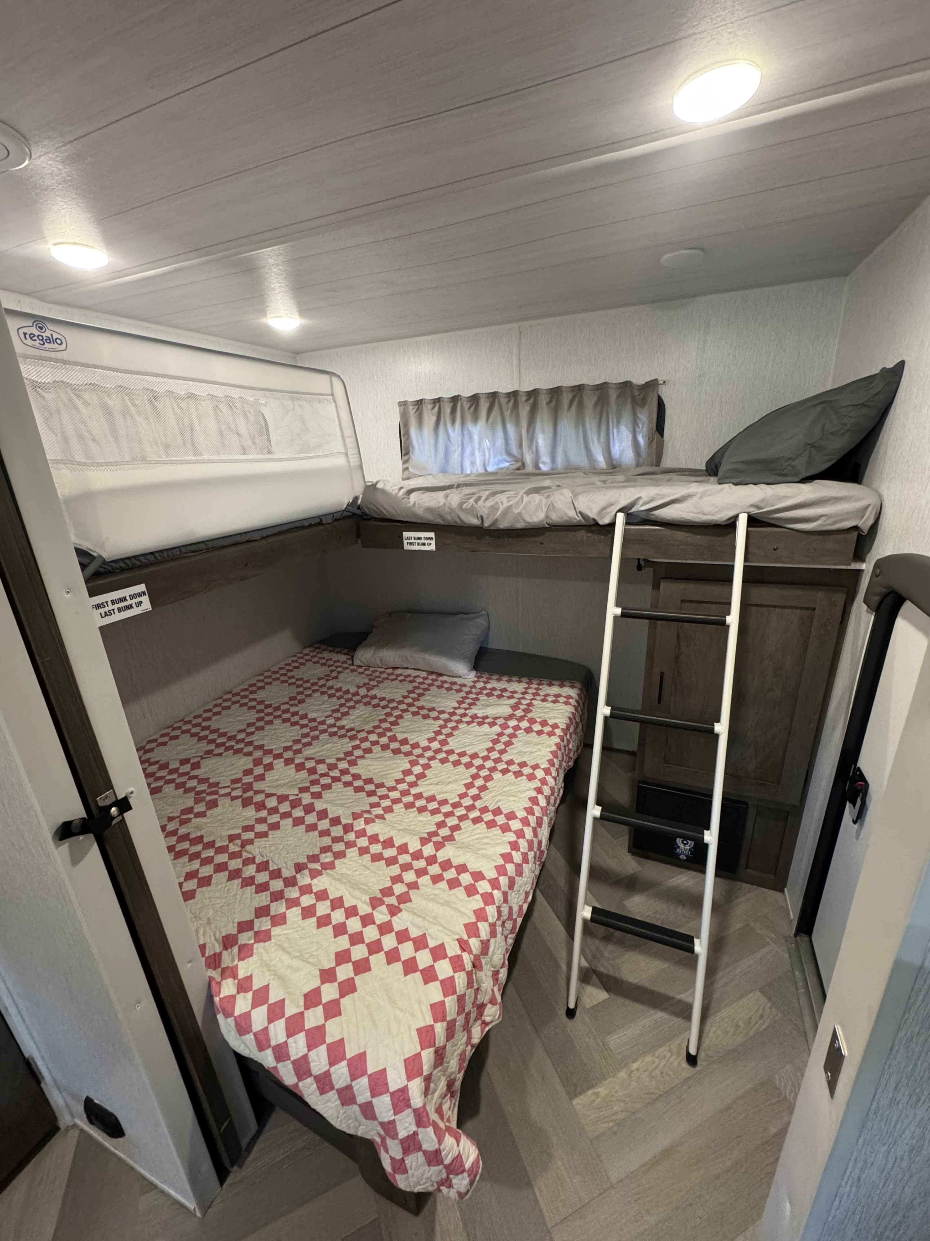 Cozy RV rental bunk beds, featuring a ladder for access, a patterned quilt on the lower bunk, and a safety rail.. Forest River Salem 2022