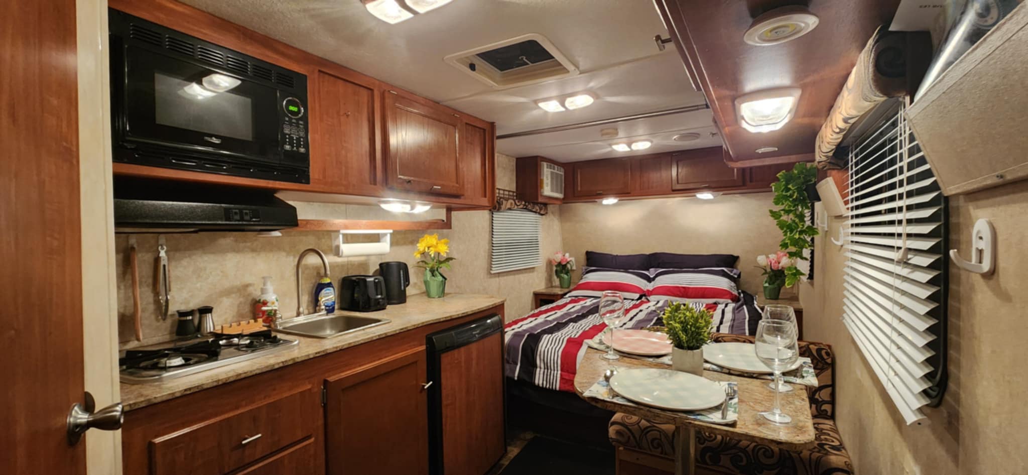 Stylish RV rental interior with a compact kitchen, comfortable bed, and set dining area.. IDEA TRAV 2013