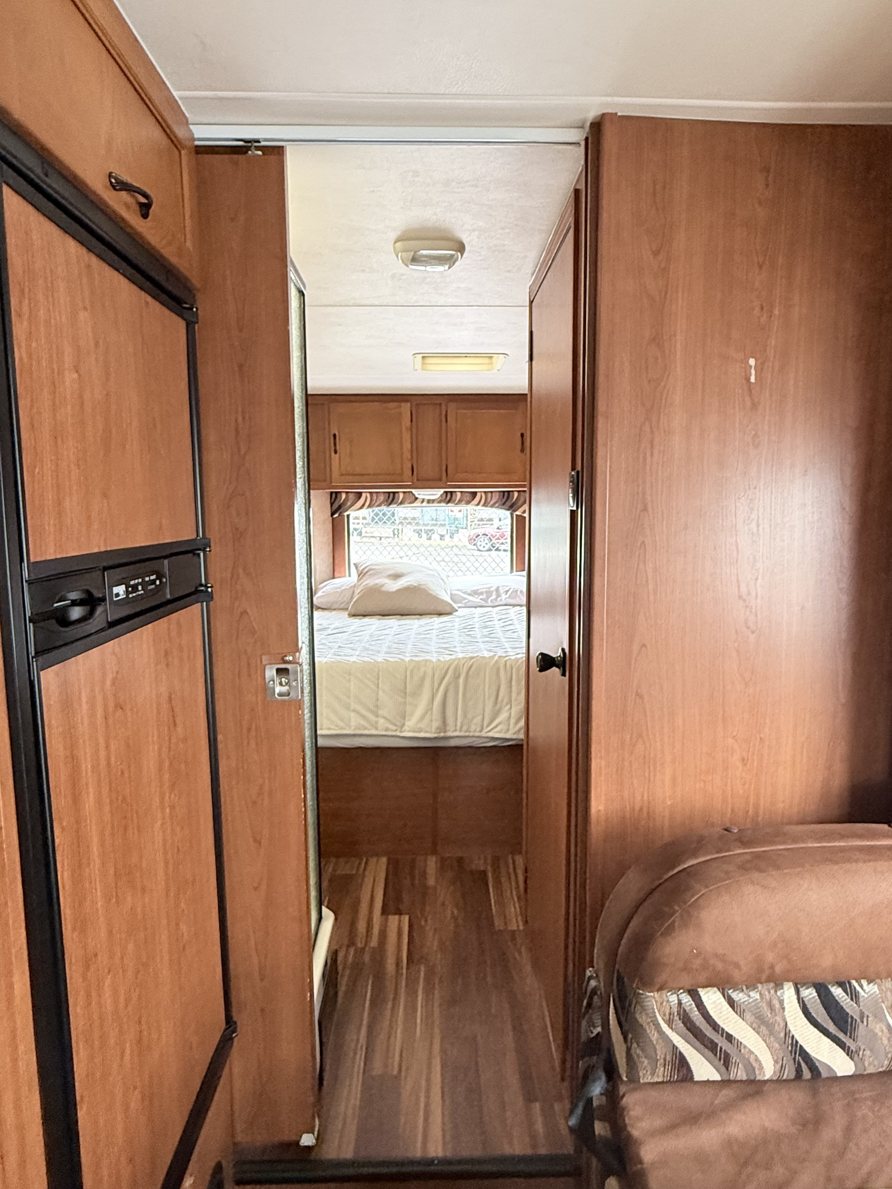 RV rental interior. Hallway view to bedroom with fridge & patterned seating. Functional and compact design.. Coachmen Freelander 2011