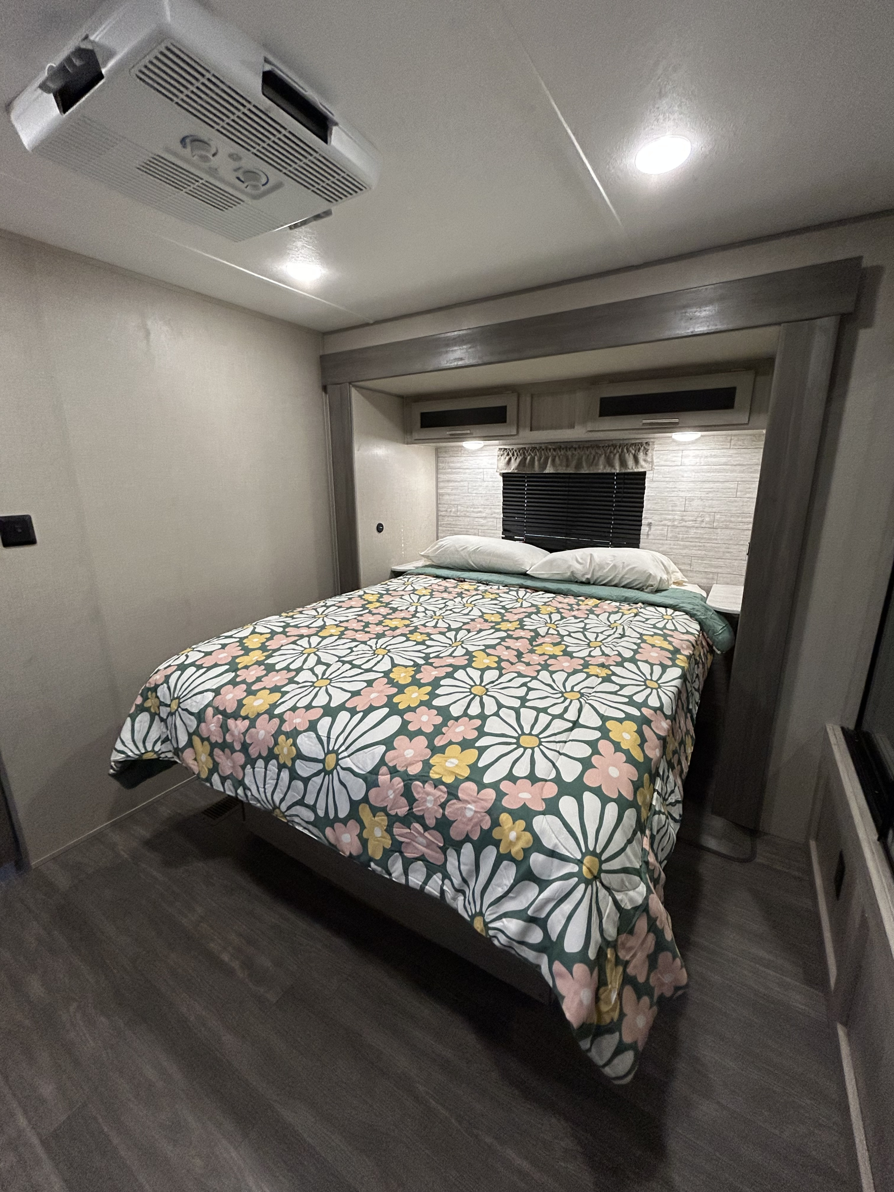 Cozy bedroom in an RV rental, featuring a vibrant floral comforter, overhead AC, and comfortable bedding.. Forest River Aurora Aurora 2023