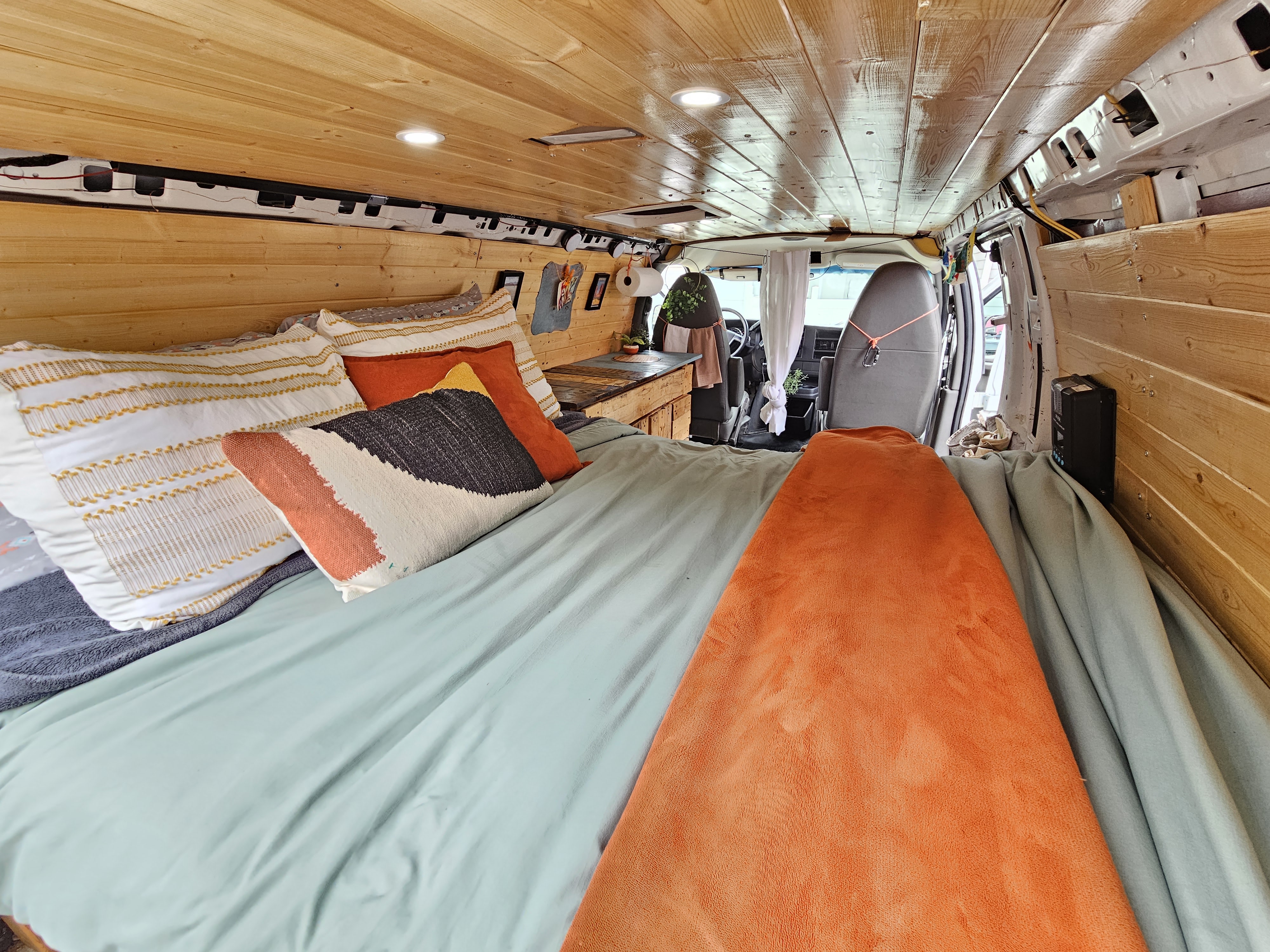 Cozy RV rental interior with wooden walls, ceiling, and a comfortable bed. Ideal for road trips.. Chevrolet Express 2500 2011