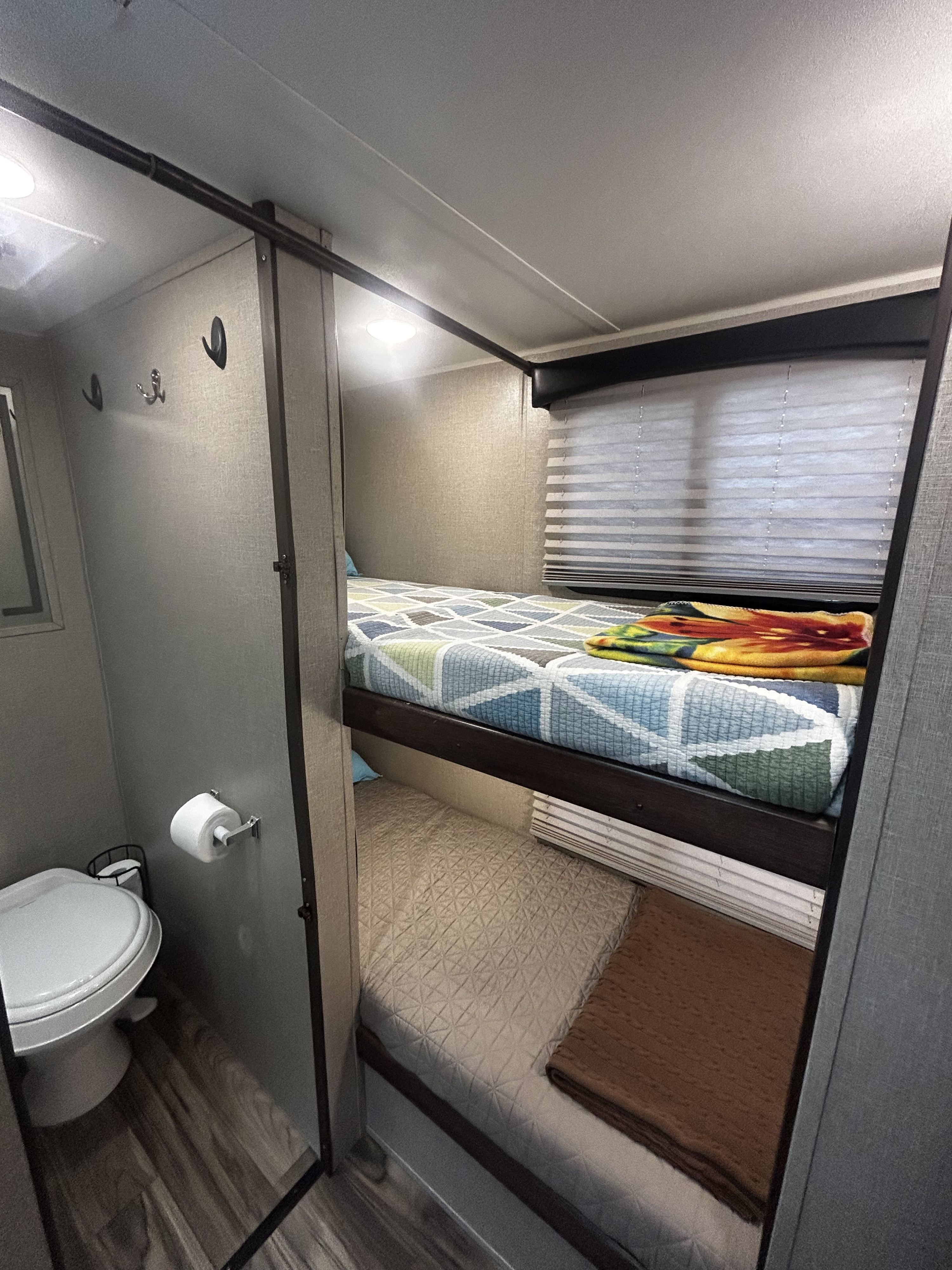 Compact RV rental interior with bunk beds and a small toilet area, maximizing space for travel adventures.. Travel Lite Falcon 2018