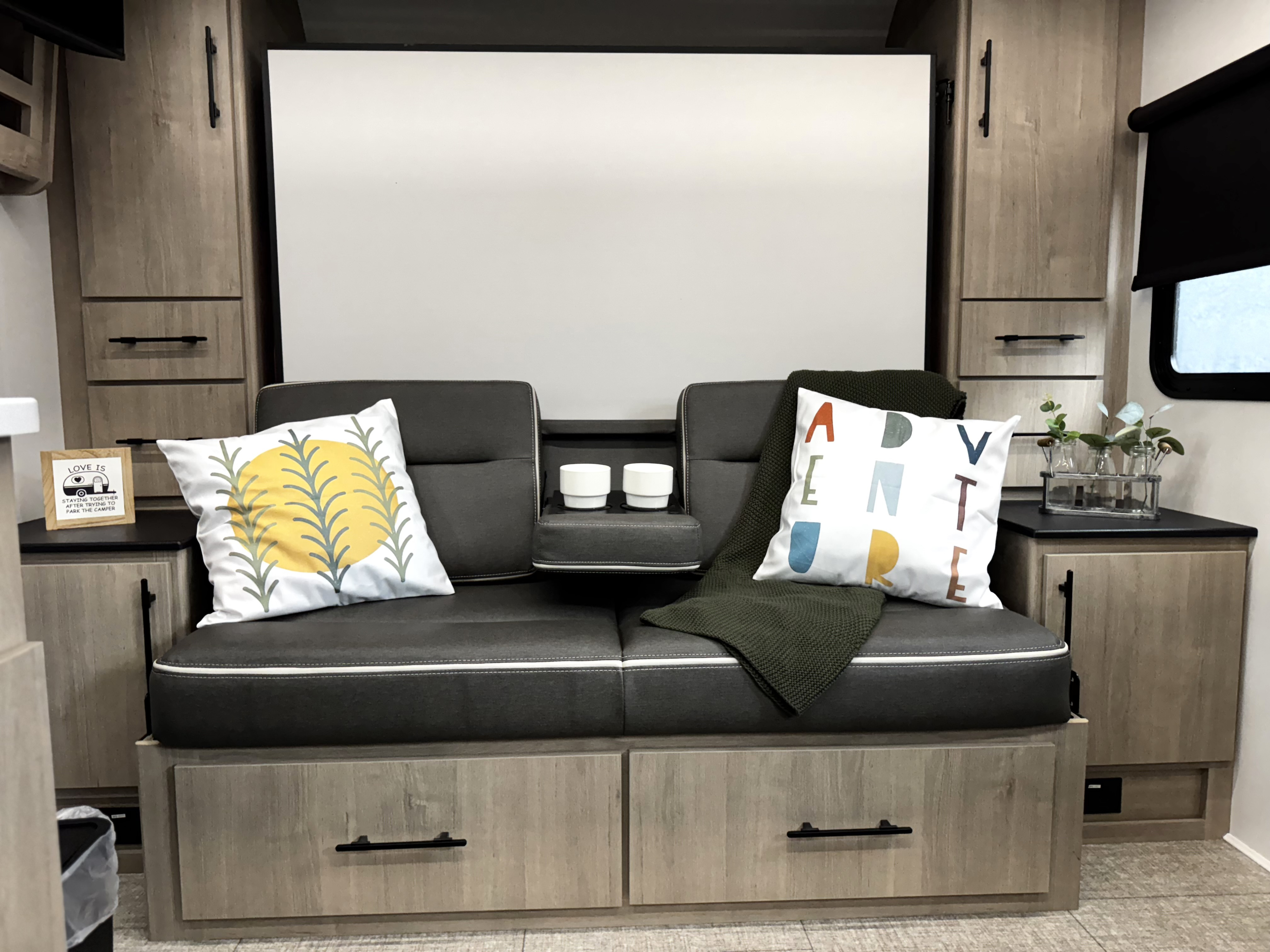 This RV rental's inviting interior features a comfy sofa with unique pillows, built-in storage, and a cozy throw.. Grand Design Imagine XLS21BHE 2025