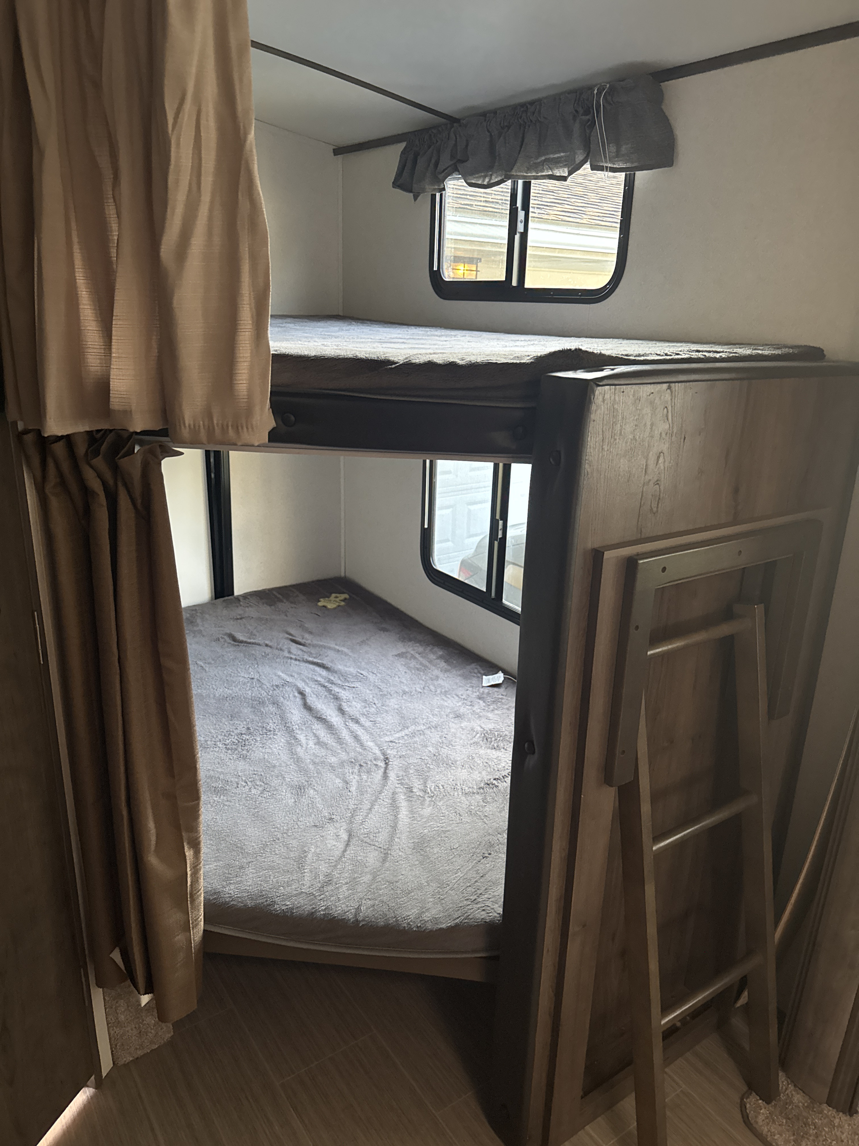 RV rental bunk beds in a cozy camper interior with a ladder for top bunk access.. Keystone RV Passport Grand Touring 2021
