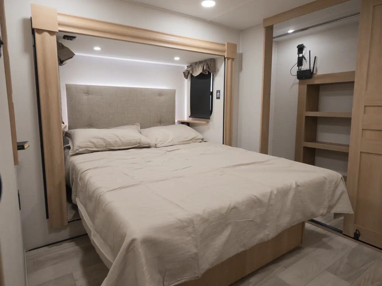 Comfortable RV rental bedroom with a neutral bed, soft headboard, and wooden built-in storage. Ideal for mobile lodging.. Forest River Sierra 2026