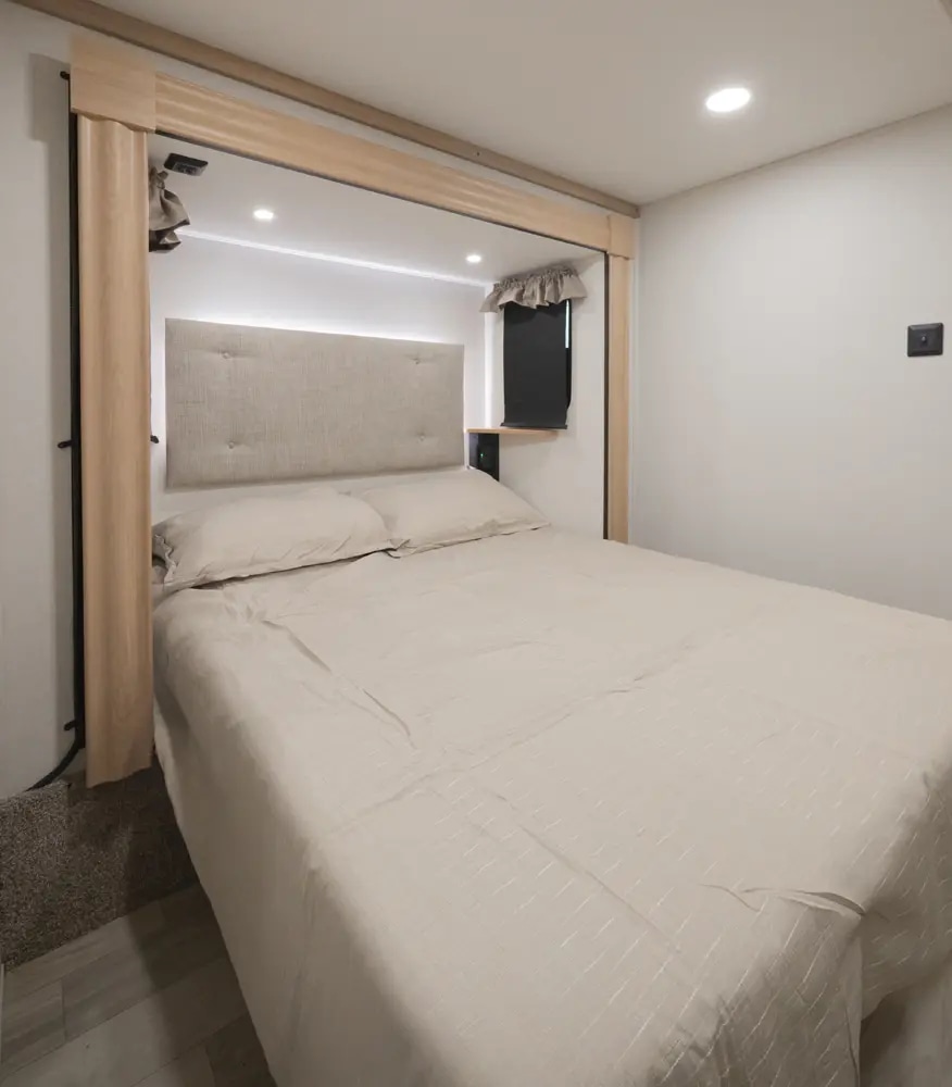 RV rental: Well-lit bedroom featuring a comfortable bed, padded headboard, and built-in amenities for travel.. Forest River Sierra 2026