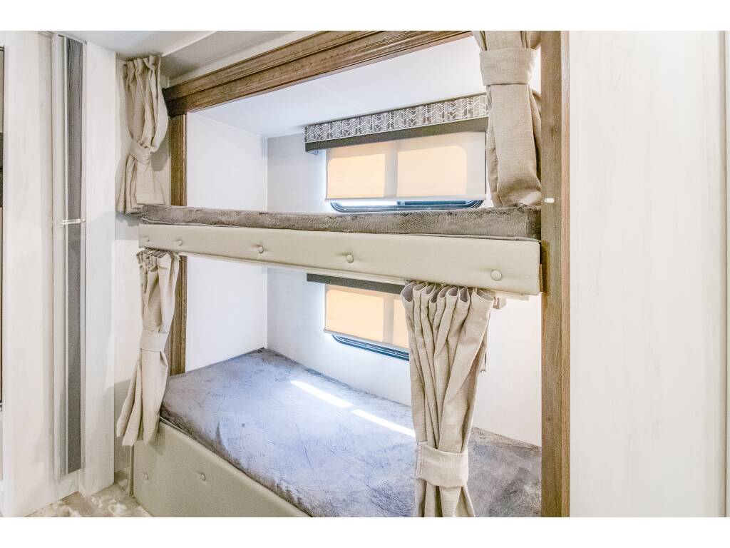 Step inside a comfortable RV rental! This image shows two bunk beds with mattresses, windows, and privacy curtains, ideal for family travel.. Gulf Stream Conquest 2023