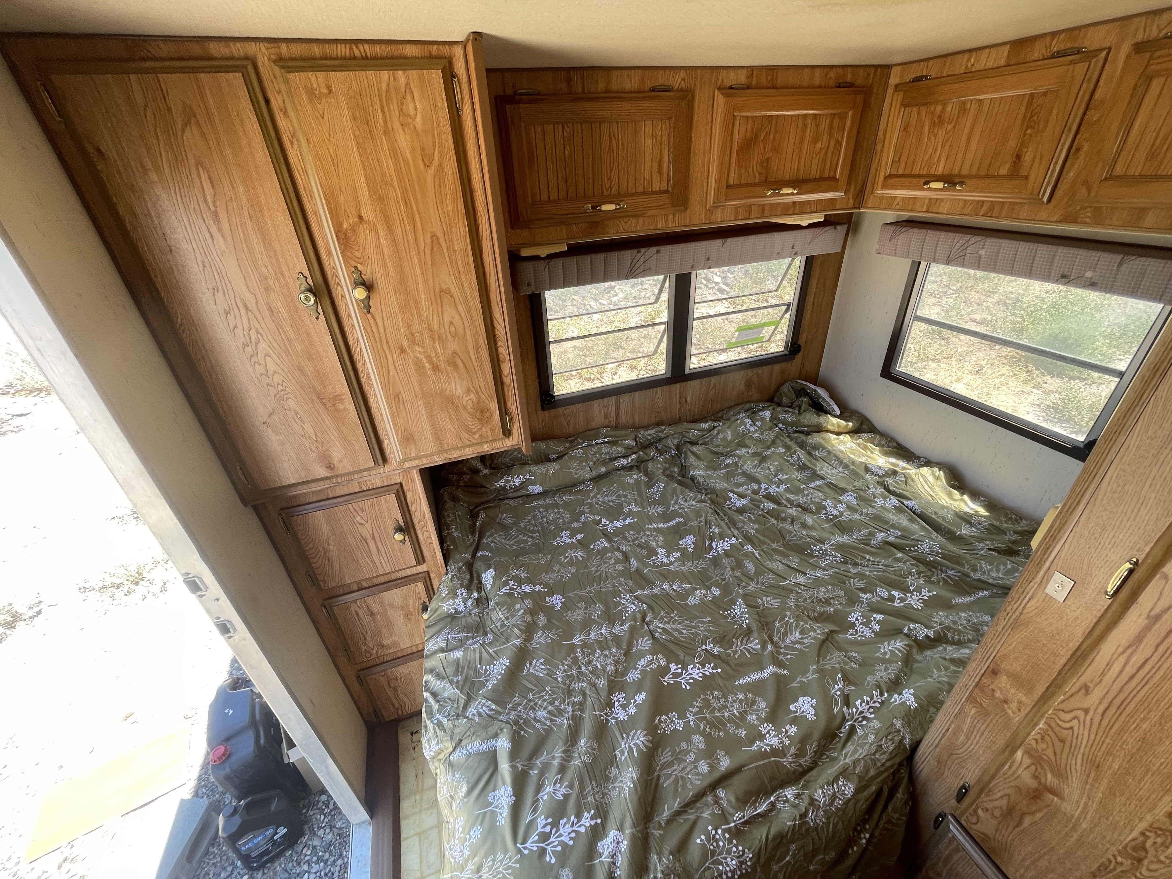 Cozy RV rental interior featuring a patterned bed, ample wood cabinets, and bright windows, perfect for your next adventure.. Skyline Aljo 1989