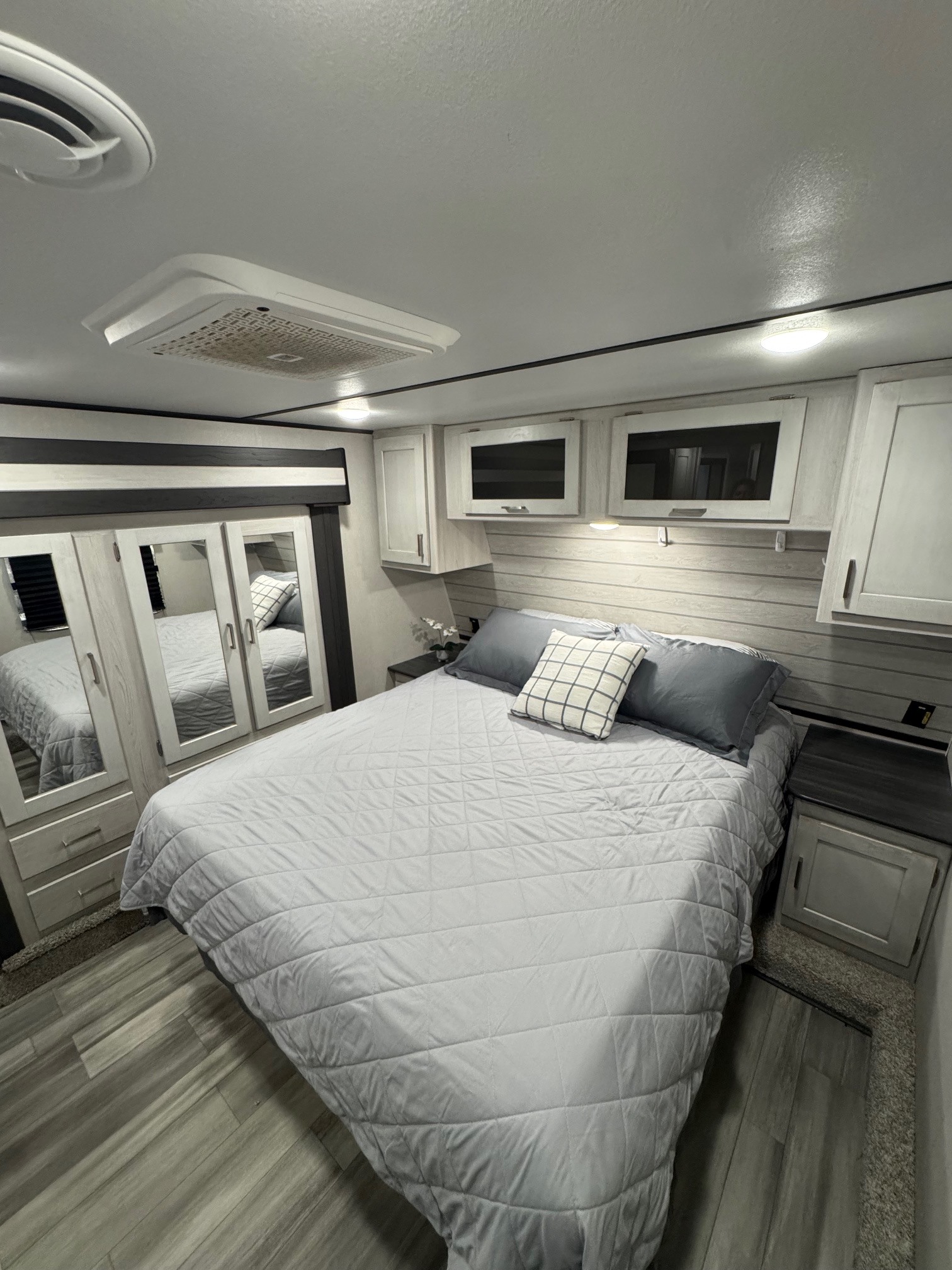 Discover comfort in this modern RV rental bedroom featuring a gray bed, ample storage, and ceiling AC.. Keystone RV Sprinter 2022