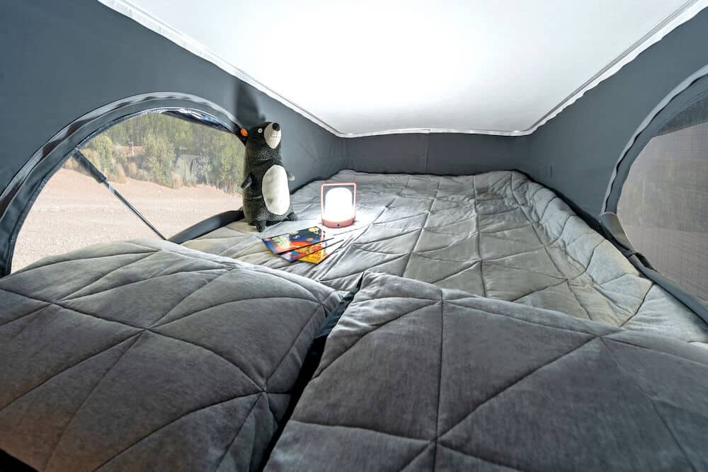 Cozy pop-top RV rental bed with a view, comfy pillows, a stuffed animal, and a light for evening reading.. Winnebago Winnebago 2023