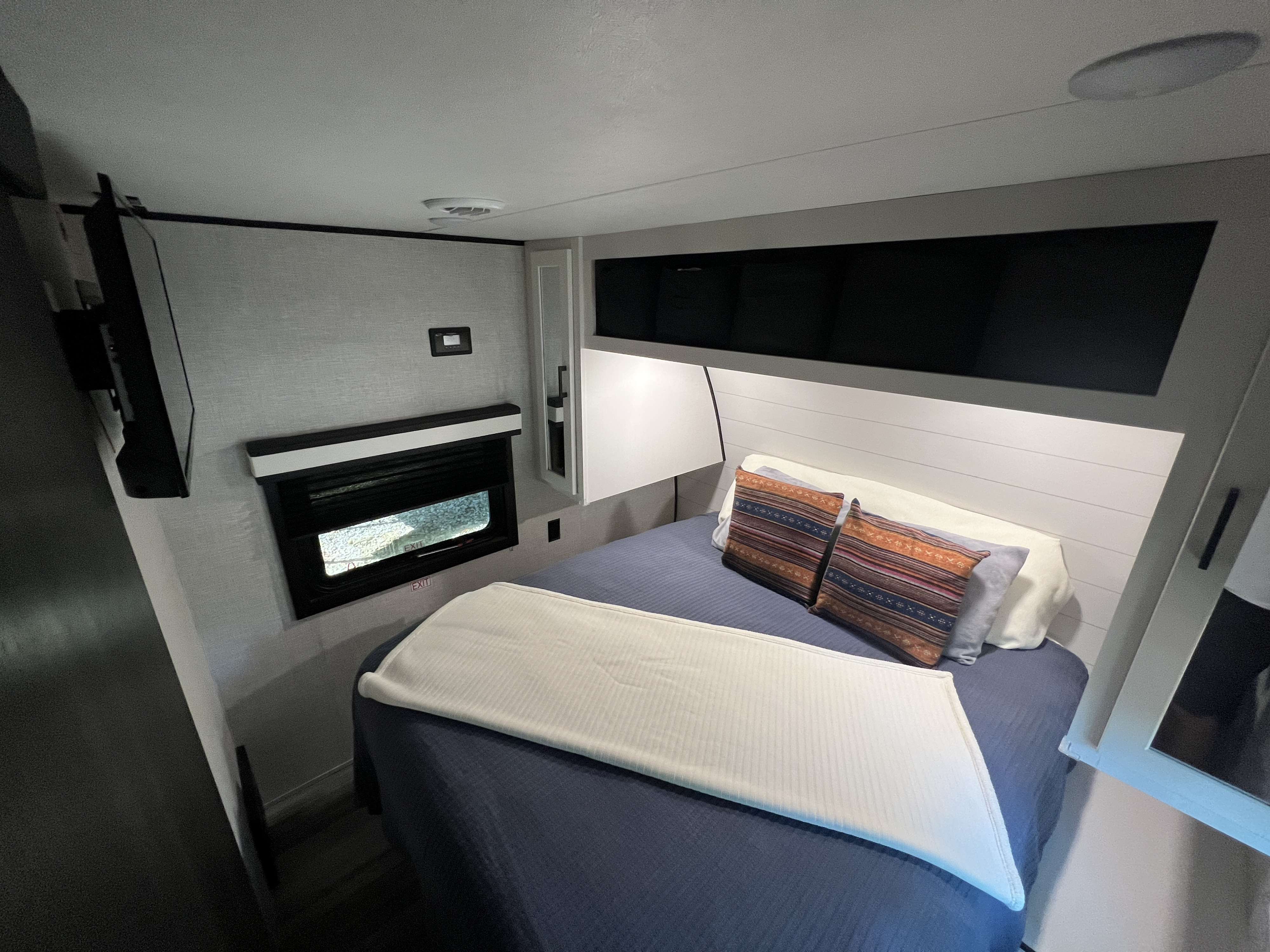 Experience comfort in this RV rental bedroom with a mounted TV, cozy bed, shiplap headboard, and compact window.. Jayco Jay Flight 2024