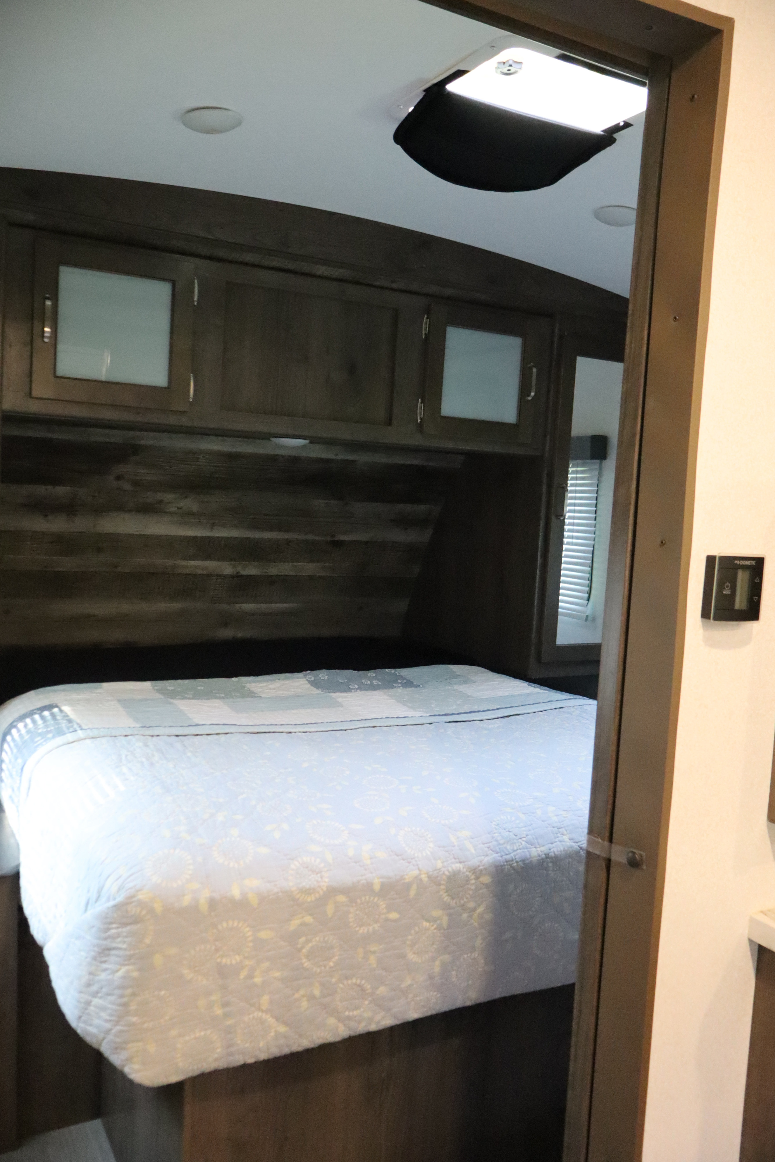 RV rental bedroom featuring a comfy bed, overhead storage, a roof vent, and Dometic climate control.. Keystone RV Passport Grand Touring 2020