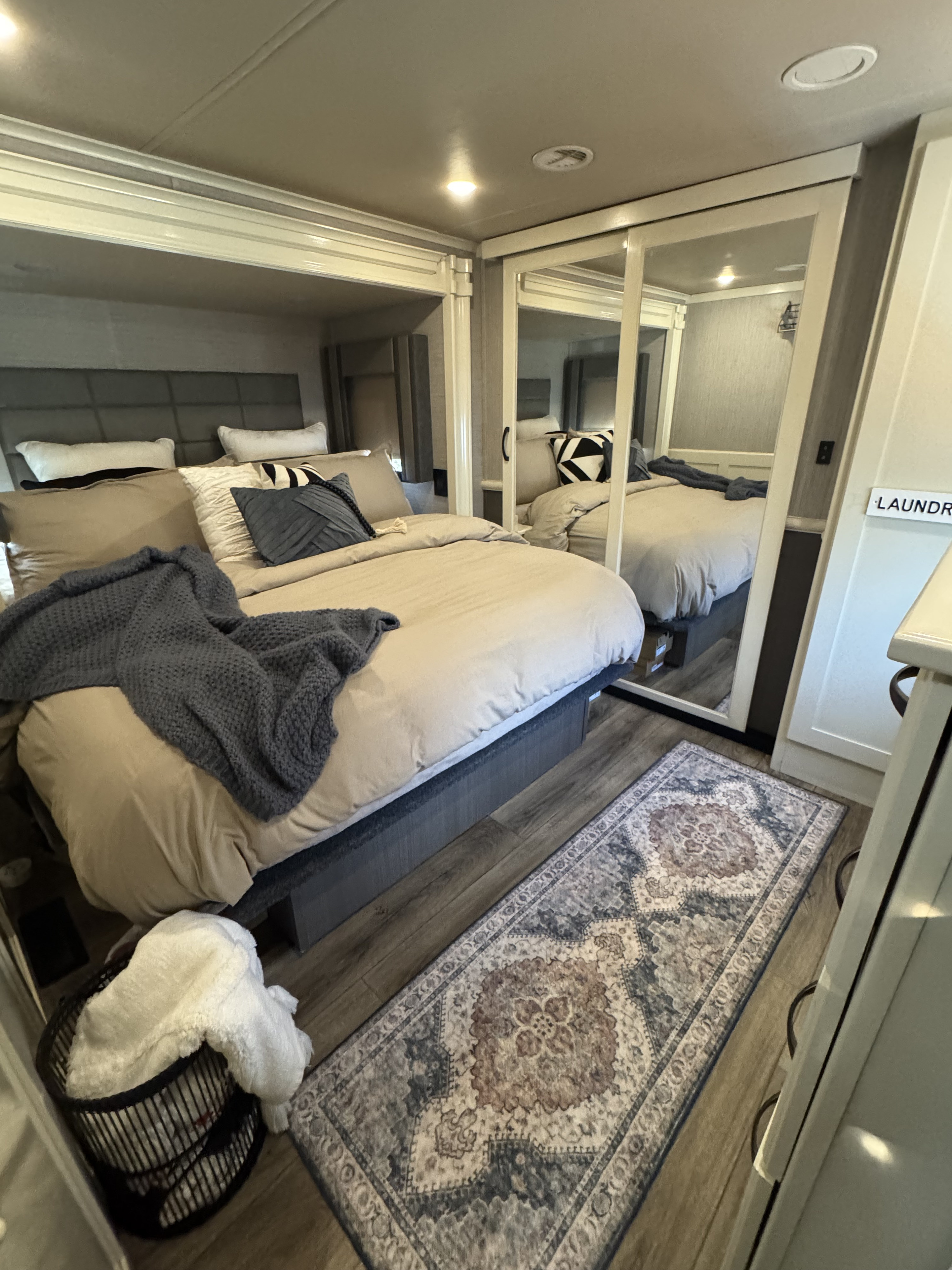 Comfortable RV rental bedroom with a beige bed, blue throw, mirrored closet doors, and patterned rug on wood floor.. Vanleigh RV Vilano 2022