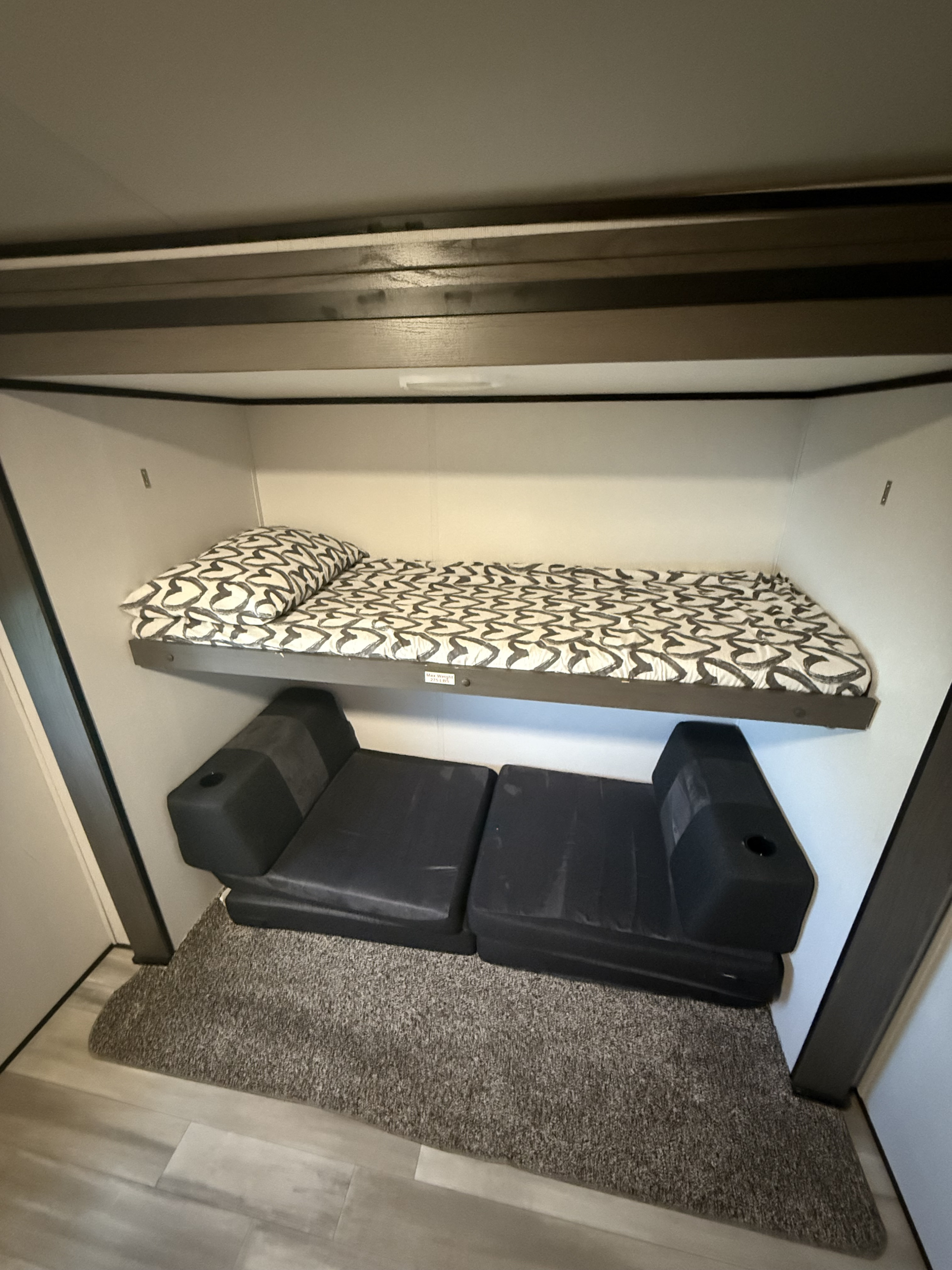 RV rental bunk area features a top bed (275 lb max) and two black modular seats below, offering versatile sleeping.. Other Other 2021