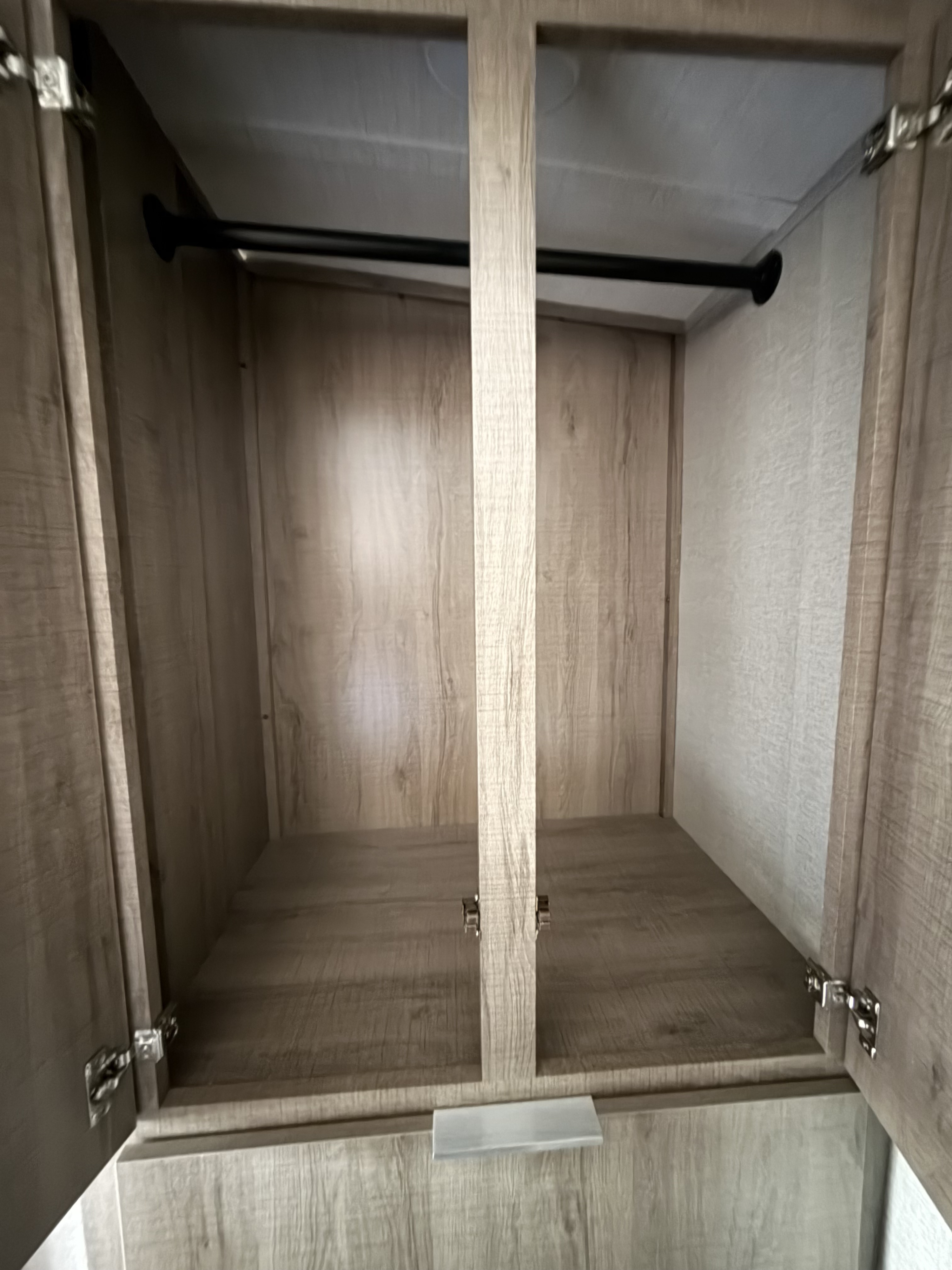 Empty wood-grain closet with a hanging rod and storage space inside an RV rental, ready for your essentials.. Grand Design Imagine 2020