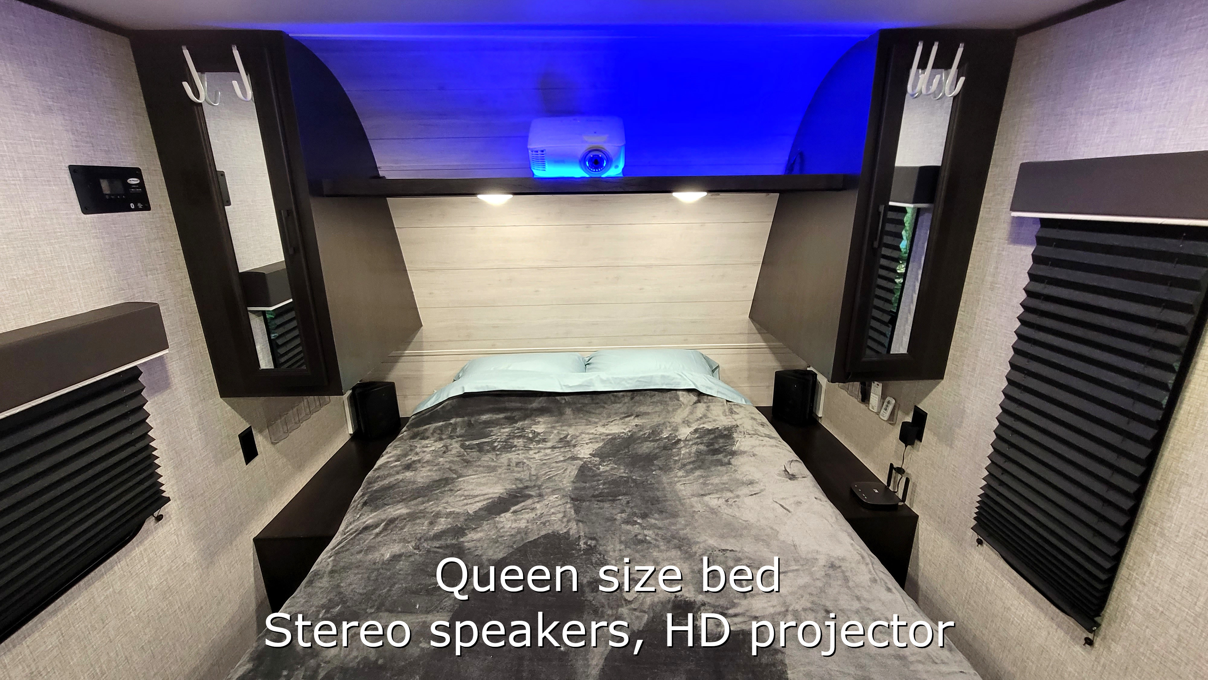 Step inside this RV rental's cozy bedroom featuring a queen bed, stereo speakers, and an HD projector with blue light.. Jayco JayFlight 224BHW 2022