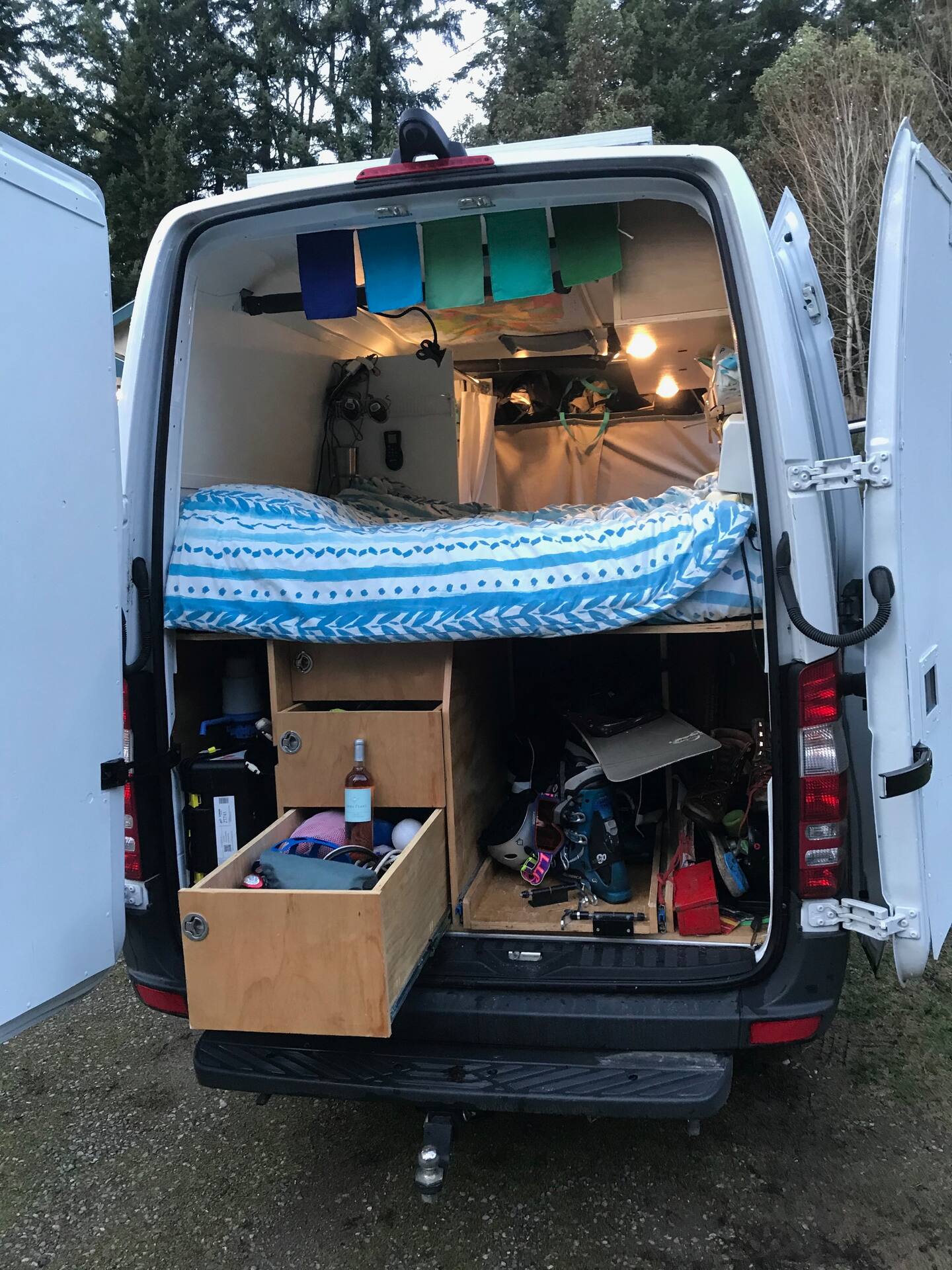 Rear view of a custom camper van conversion with a comfortable bed, smart storage drawers, and adventure gear. Ideal for rv rental.. Mercedes-Benz Sprinter RV Motorhome Campervan 2018