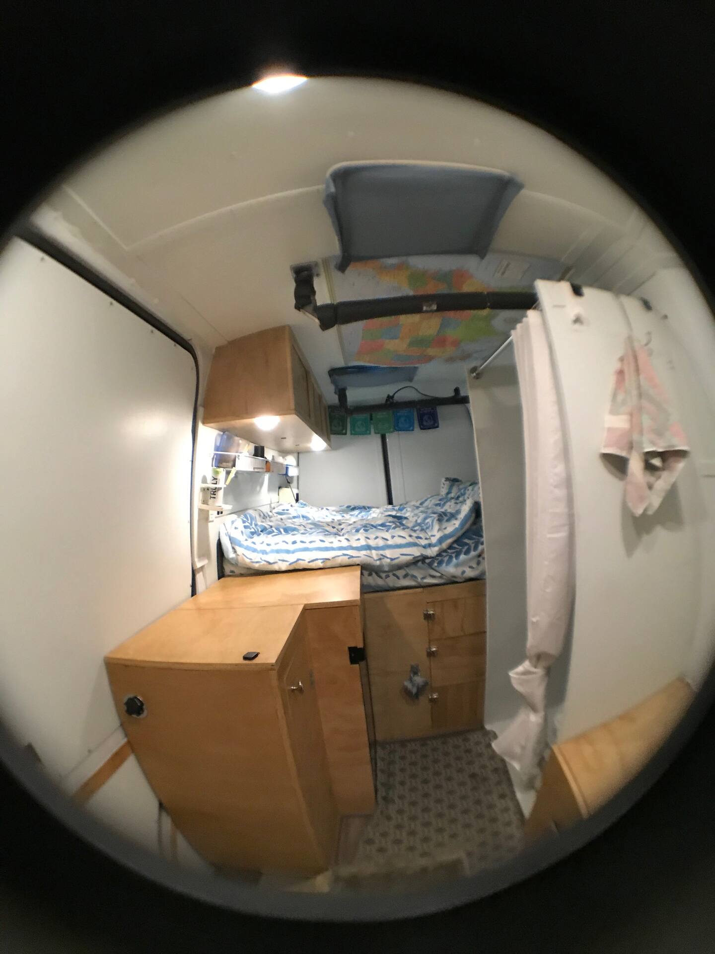 Fisheye view of this compact RV rental conversion: bed, wooden cabinets, map, and shower inside a cozy mobile home.. Mercedes-Benz Sprinter RV Motorhome Campervan 2018