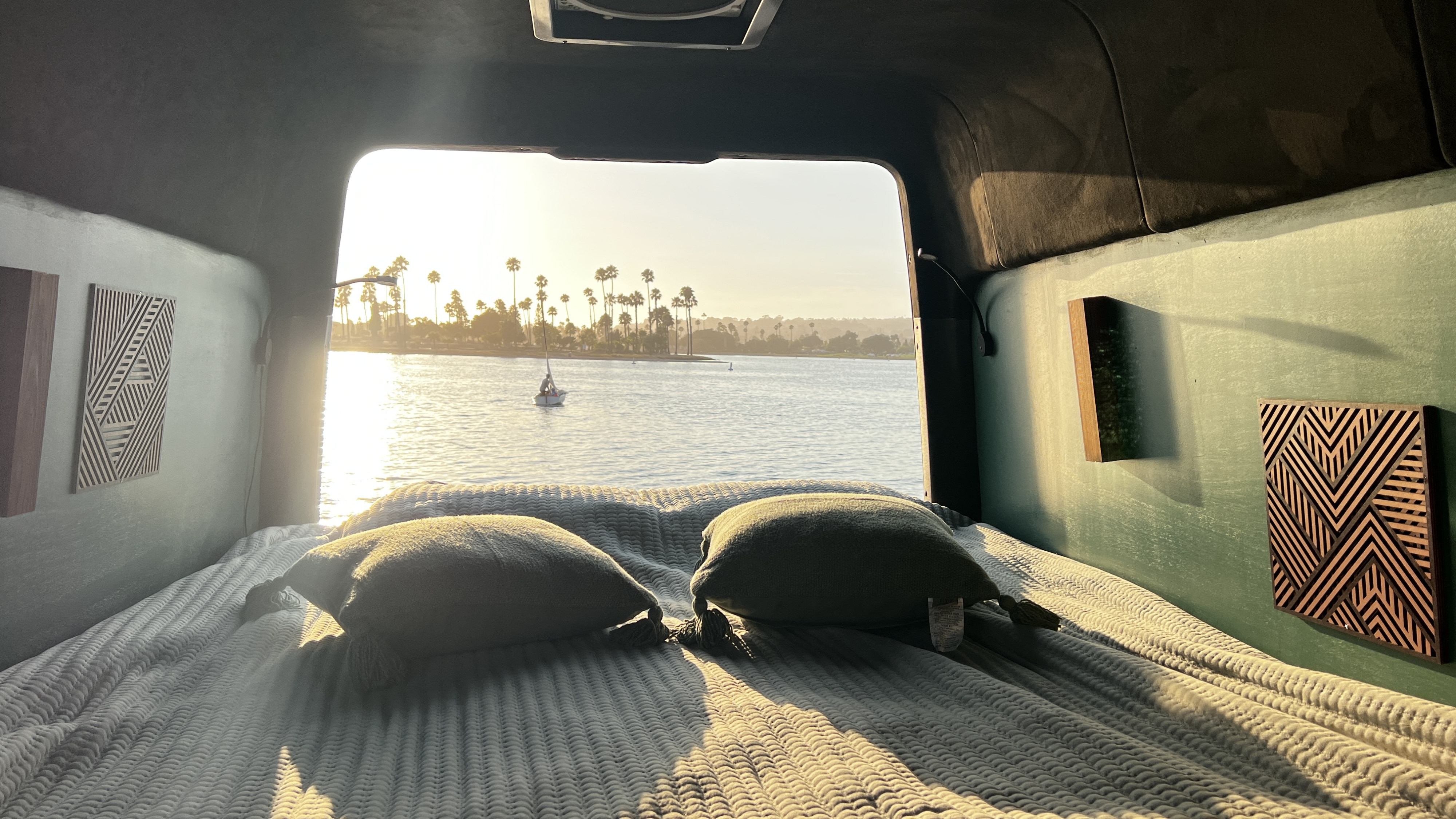 Cozy RV rental bed with a stunning water view. Enjoy serene sunsets, sailboats, and palm trees from your van life retreat.. Mercedes-Benz Sprinter 2024