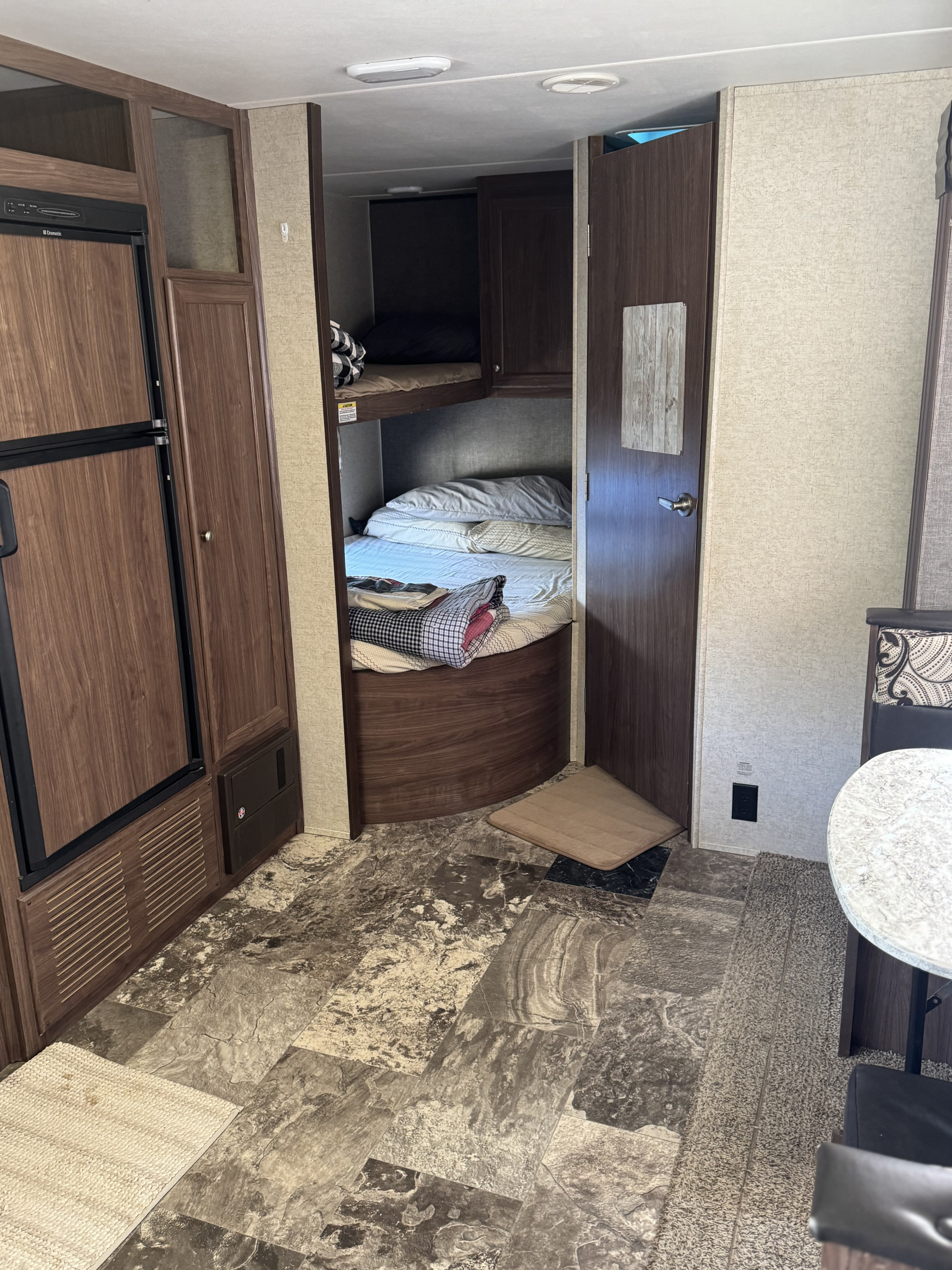 Compact RV rental interior featuring bunk beds, a kitchen area with fridge, and durable patterned flooring for travel.. Heartland RVs Prowler Lynx 2016