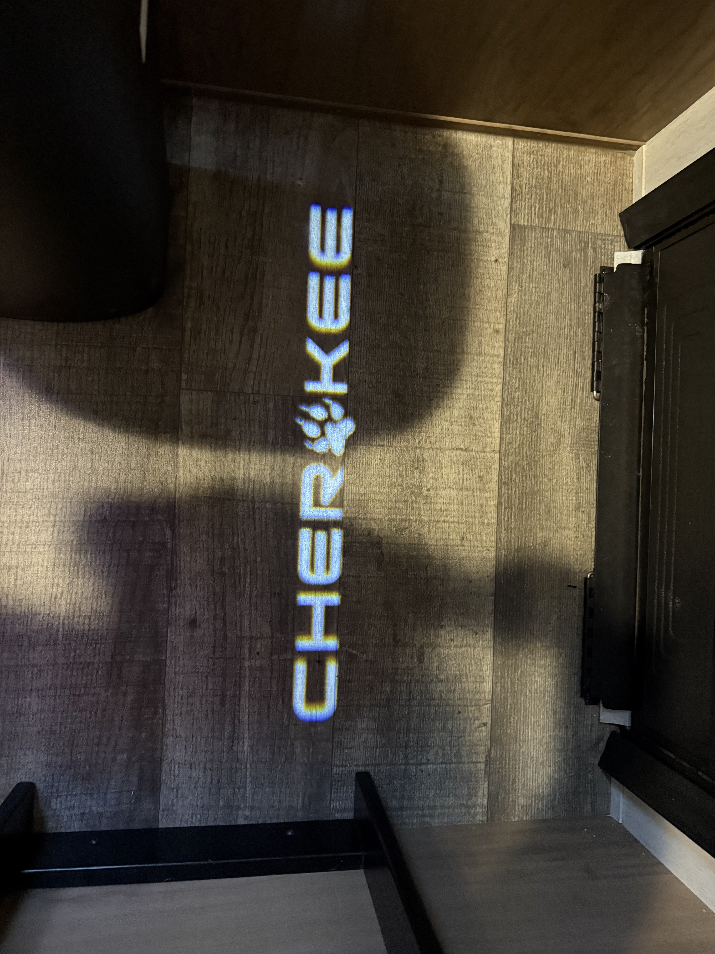 Illuminated Cherokee paw print logo projected on an RV rental's wooden floor. A vehicle's custom light feature.. Forest River Cherokee 2023