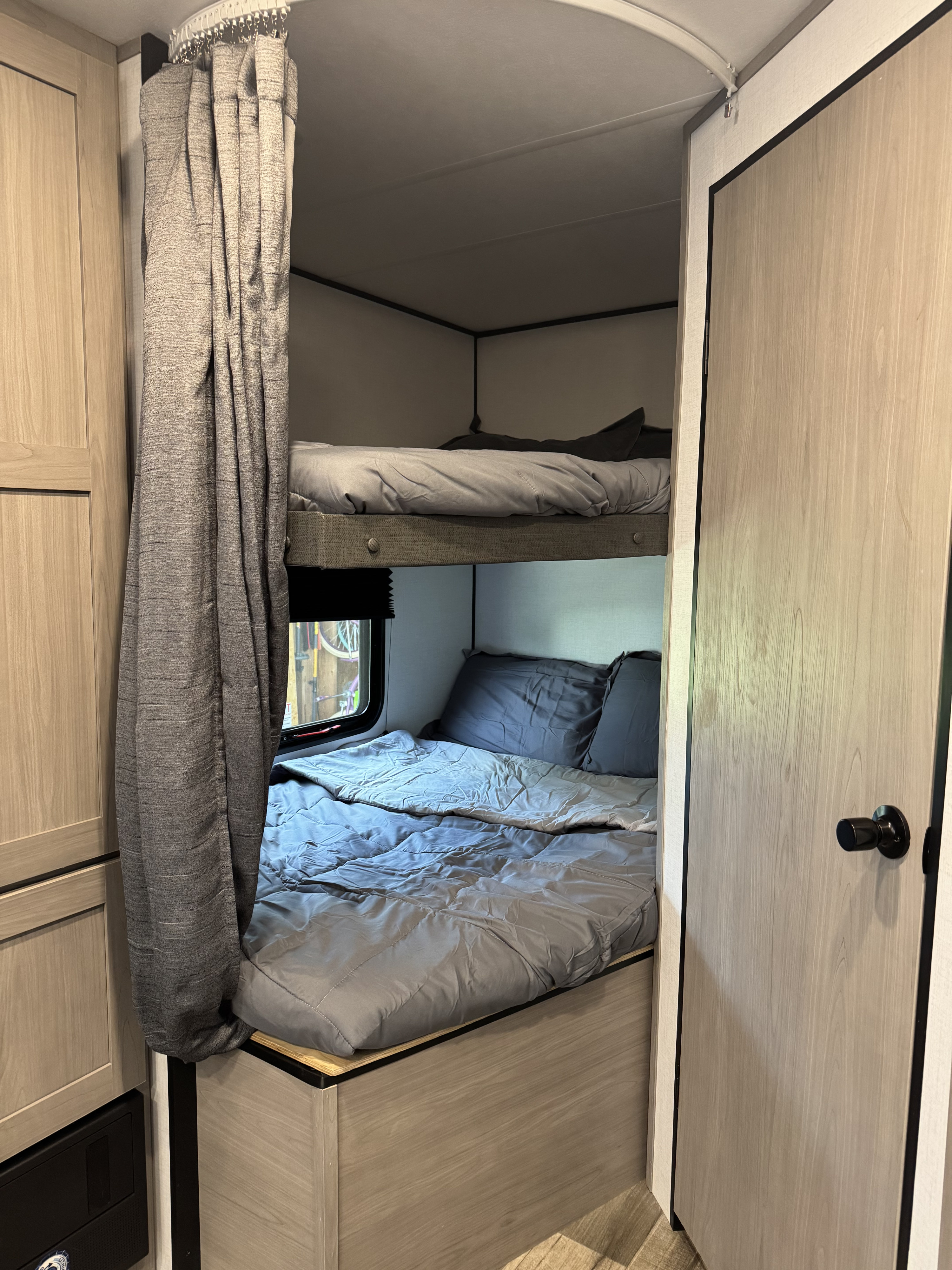 Cozy RV rental interior with comfortable bunk beds and privacy curtain, perfect for family travel.. Dutchmen Coleman lantern 262BH 2024