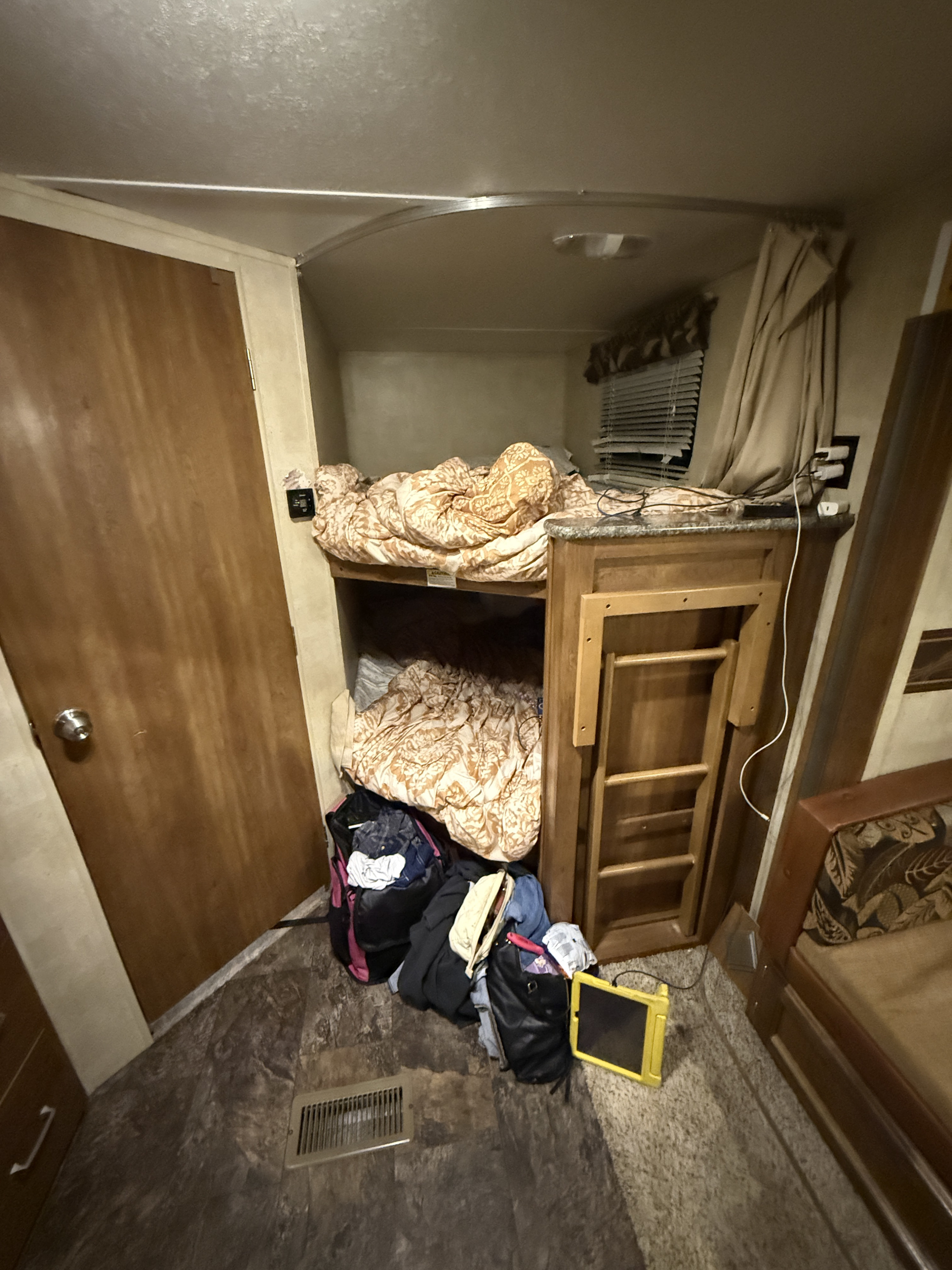 Cozy RV rental interior with a bunk bed, lower storage, door, and folded ladder for compact living.. Keystone RV Springdale 2014
