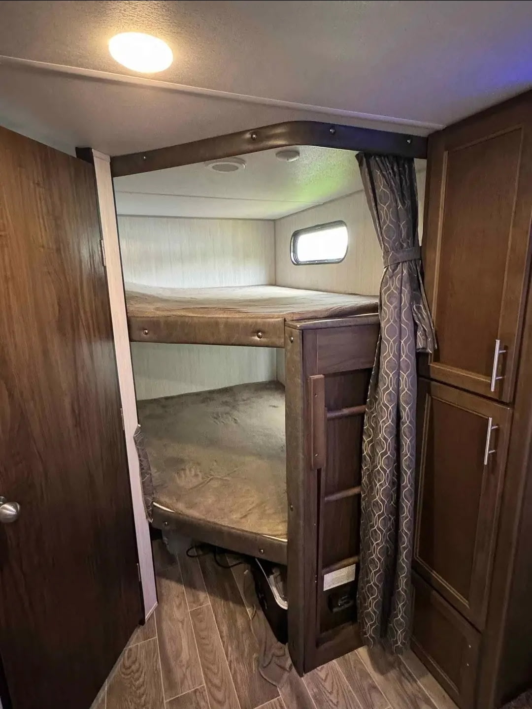 RV rental interior: cozy bunk beds in a camper's sleeping area. Ideal for family trips, offering comfort & privacy.. Forest River Cherokee Grey Wolf 2019
