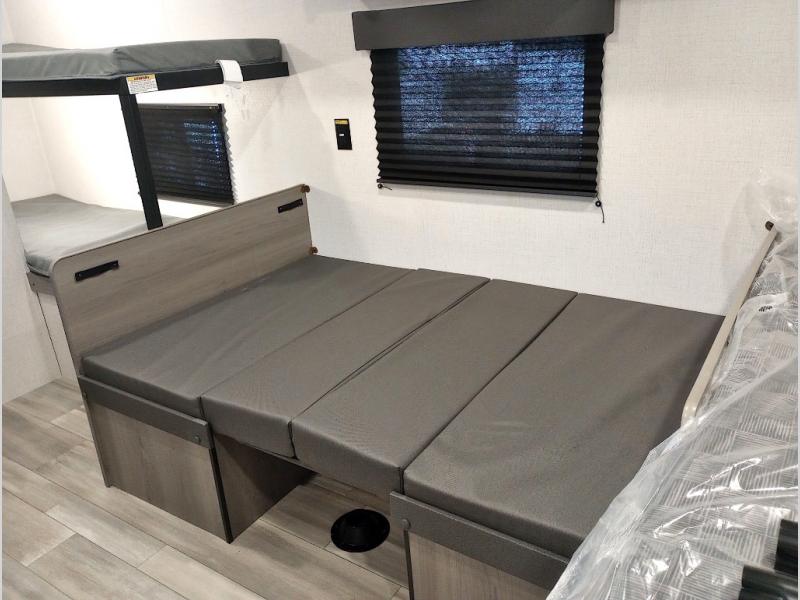 **RV rental** interior featuring bunk beds and a gray cushioned convertible dinette that forms a bed.. Keystone RV Hideout Sport 2024