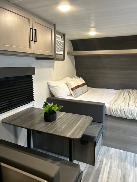 RV rental: Modern interior shows a dining table with benches, a cozy bed, and overhead storage, all in muted tones.. Keystone RV Hideout Sport 2024