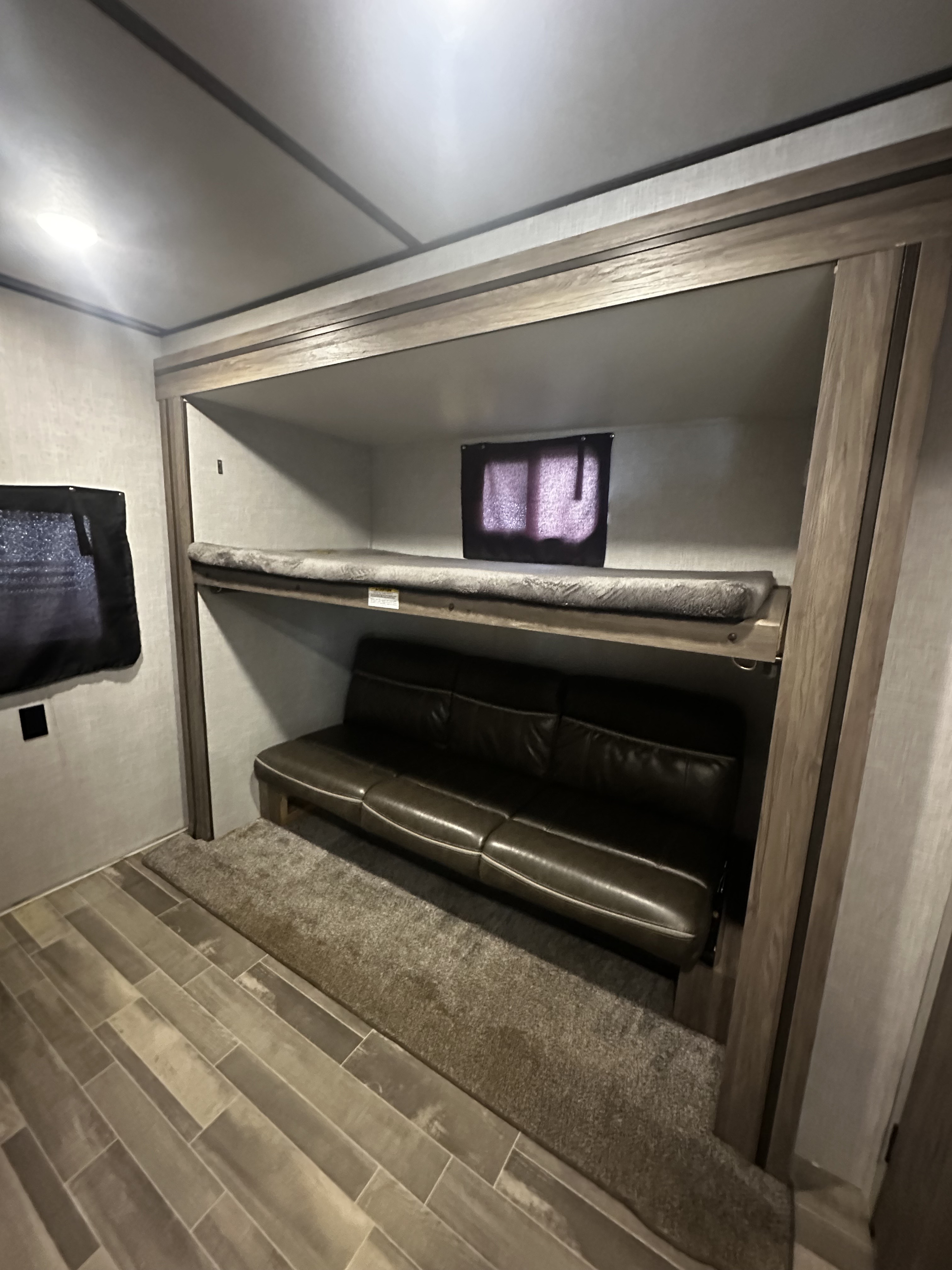 RV rental: bunk beds above a brown sofa. Wood-look floor & rug in cozy interior.. Crossroads RV Zinger 2020